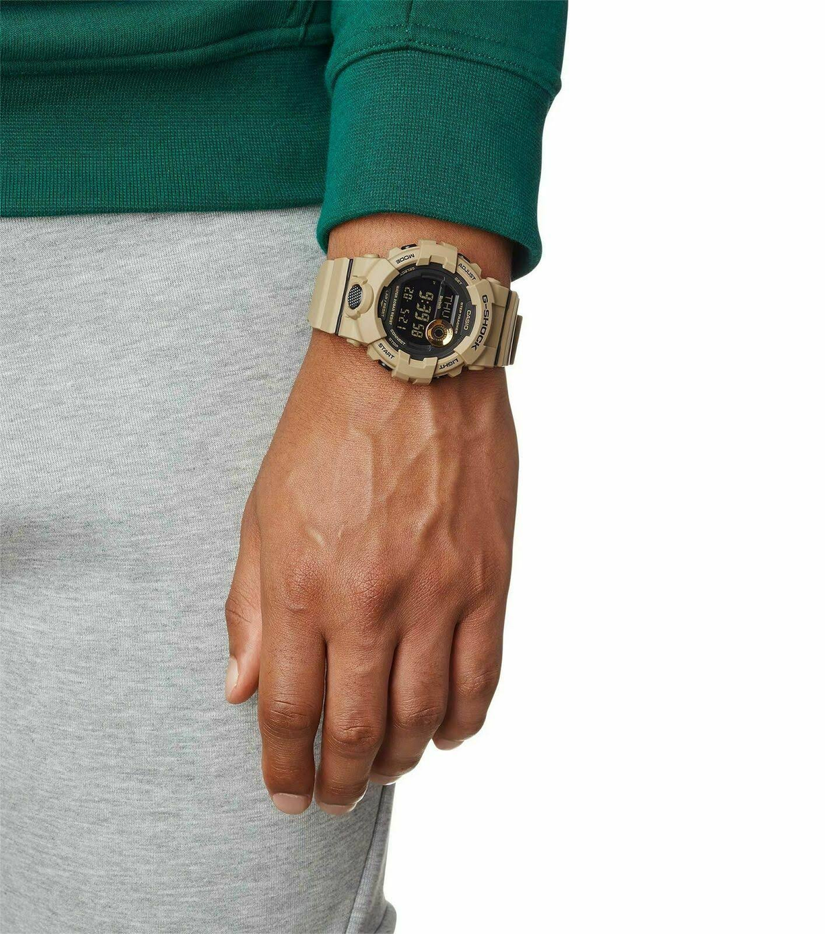 Un reloj G-Shock beige con pantalla digital se lleva en una muñeca.