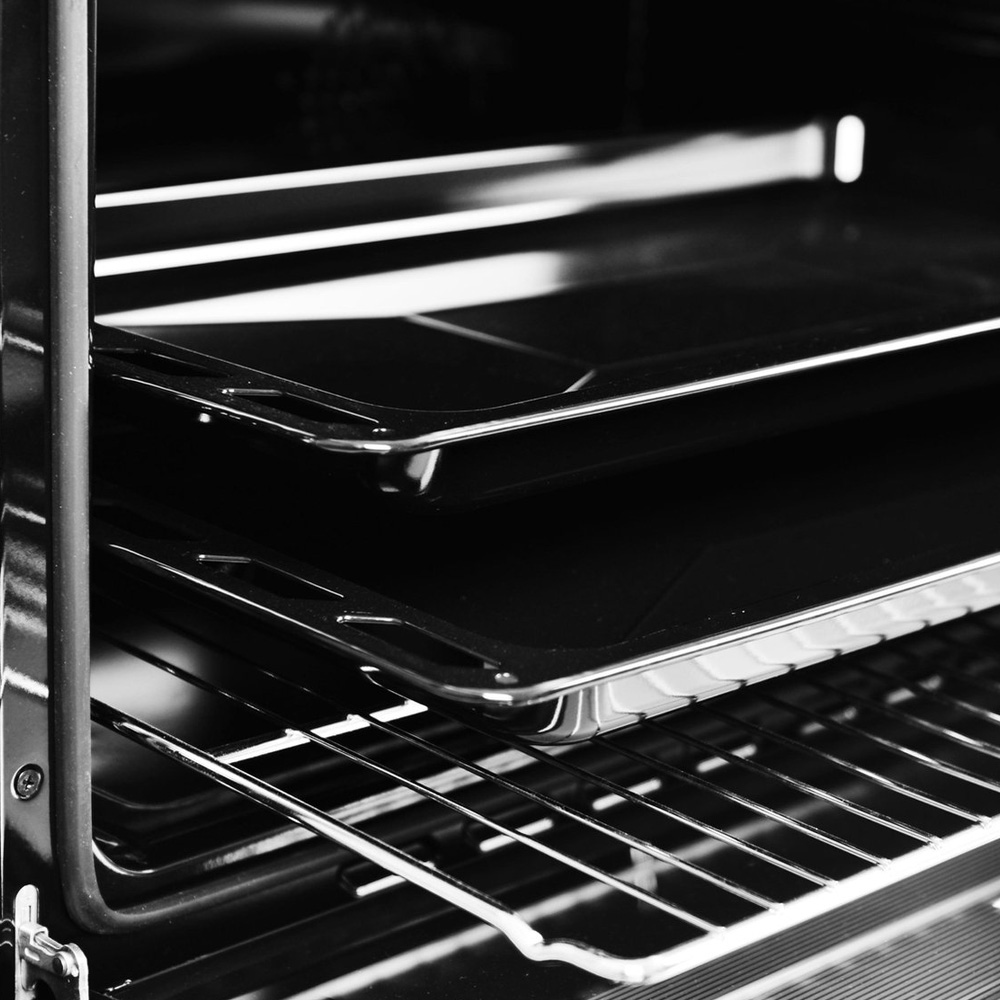 Close-up of the inside of a black oven with two baking sheets and a rack.