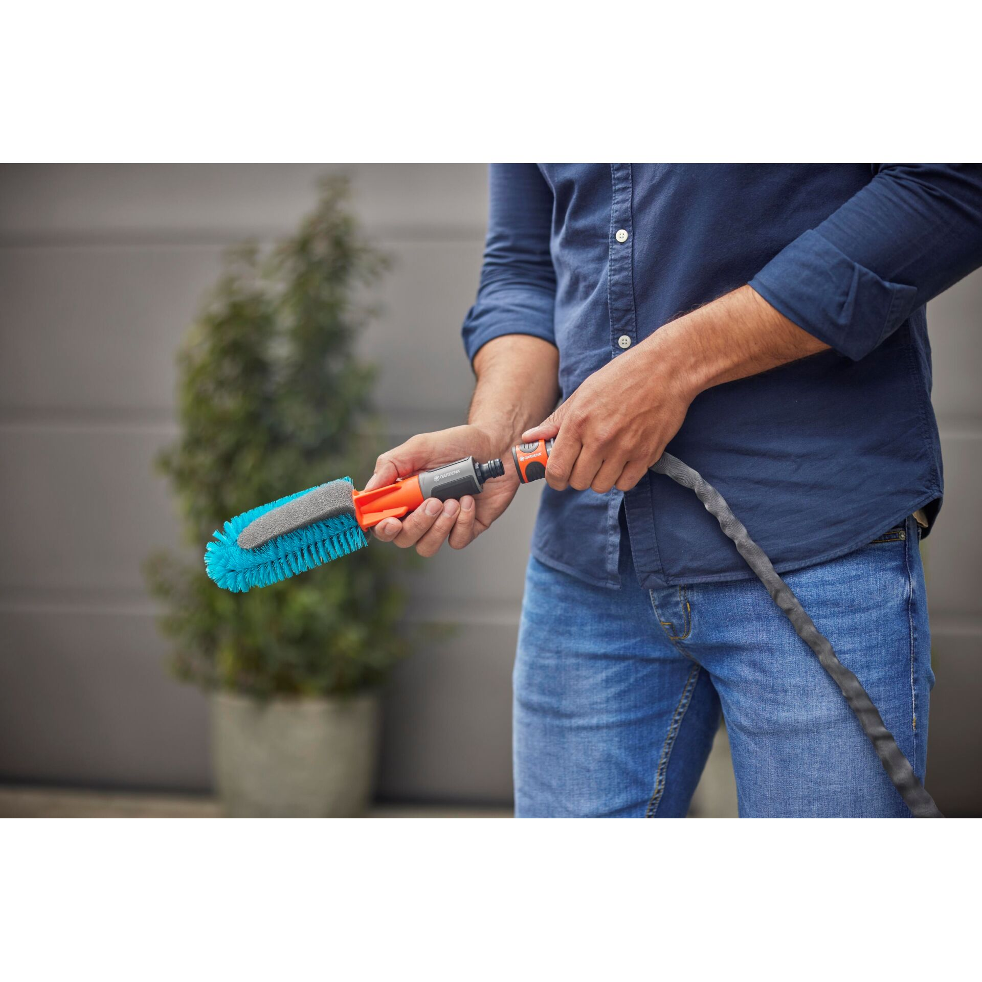 Uomo collega tubo da giardino a spazzola blu.