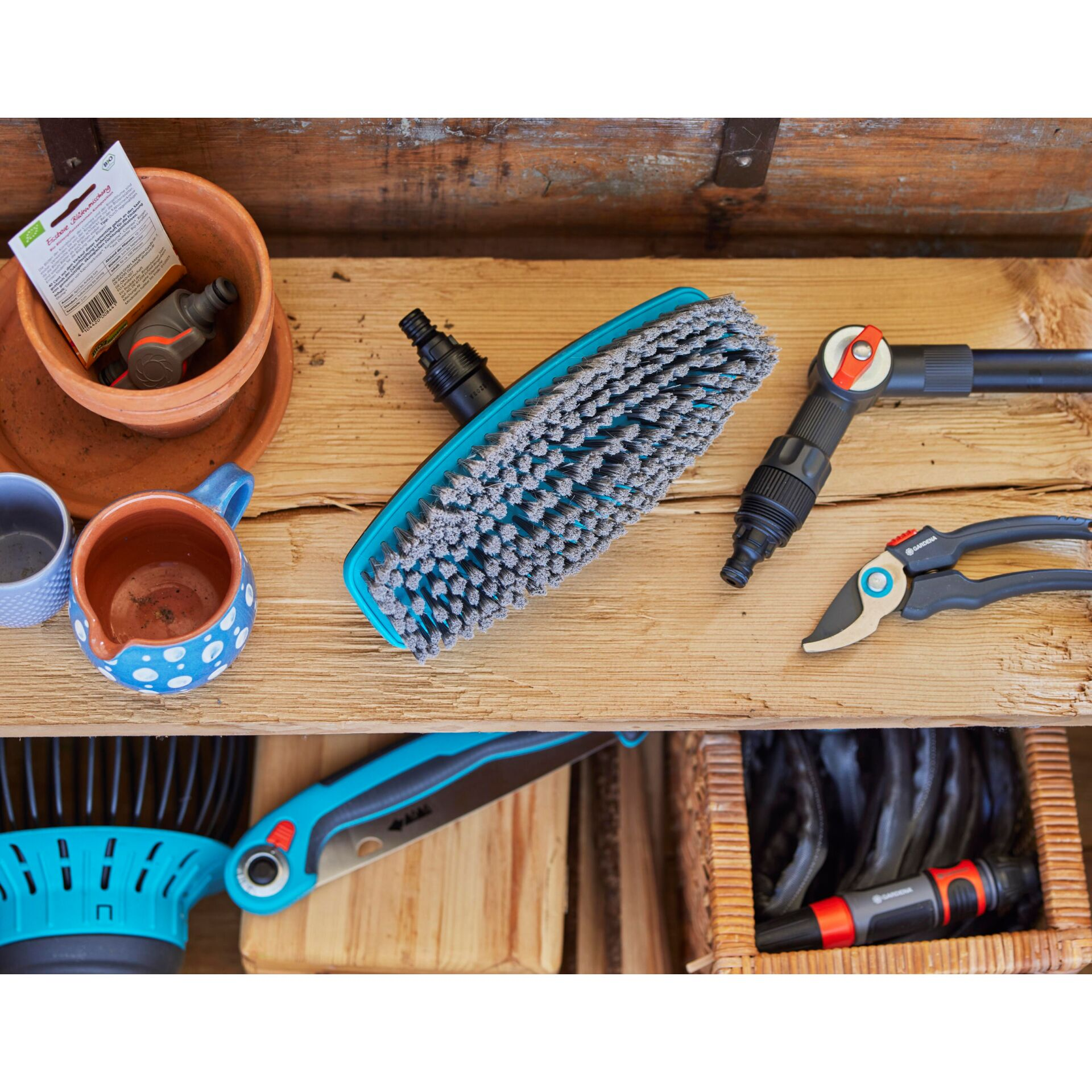 Tuimgereedschap zoals schaar, borstelkop en slangkoppelingen op houten plank.