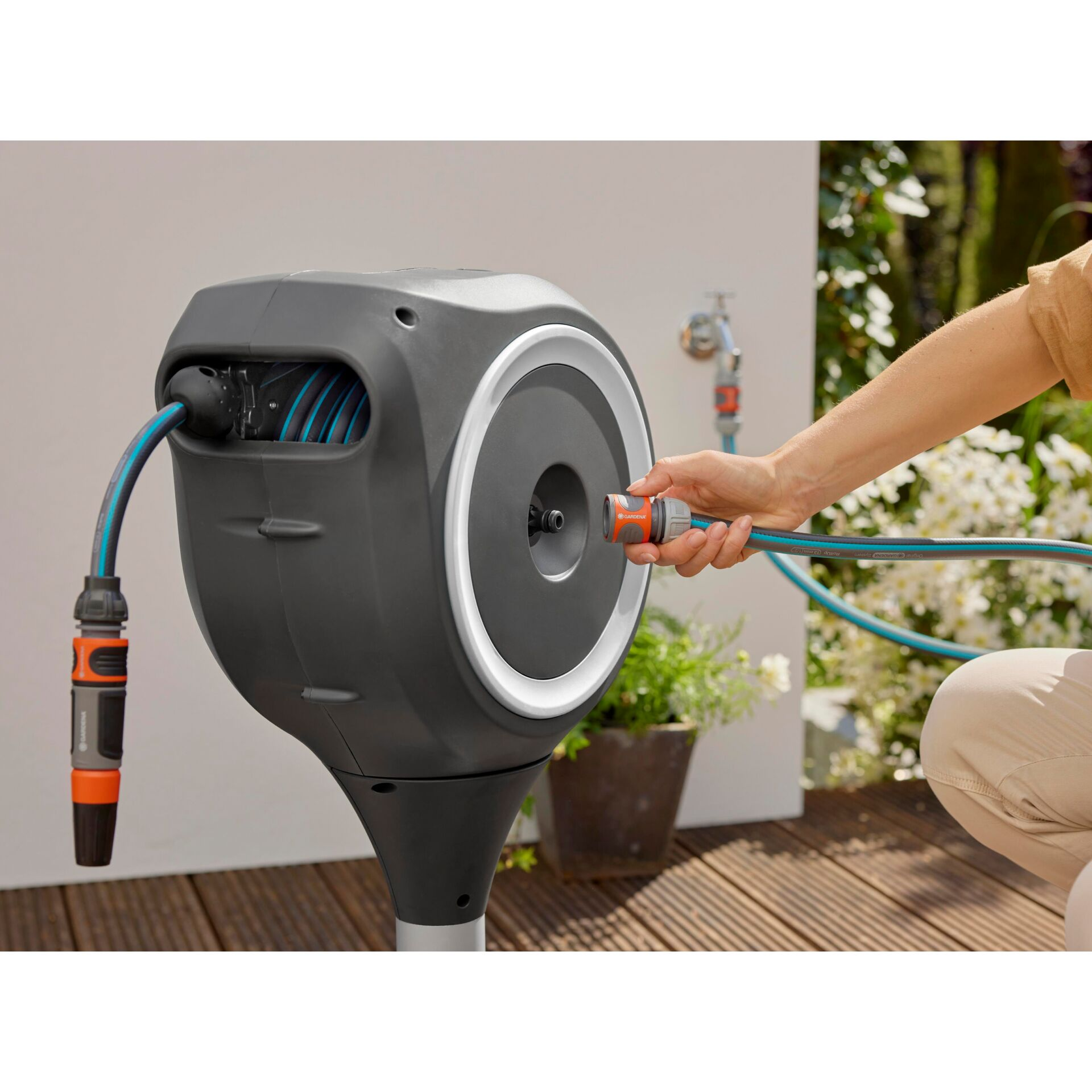 Eine Hand verbindet einen Gartenschlauch mit einem automatischen Schlauchaufroller.