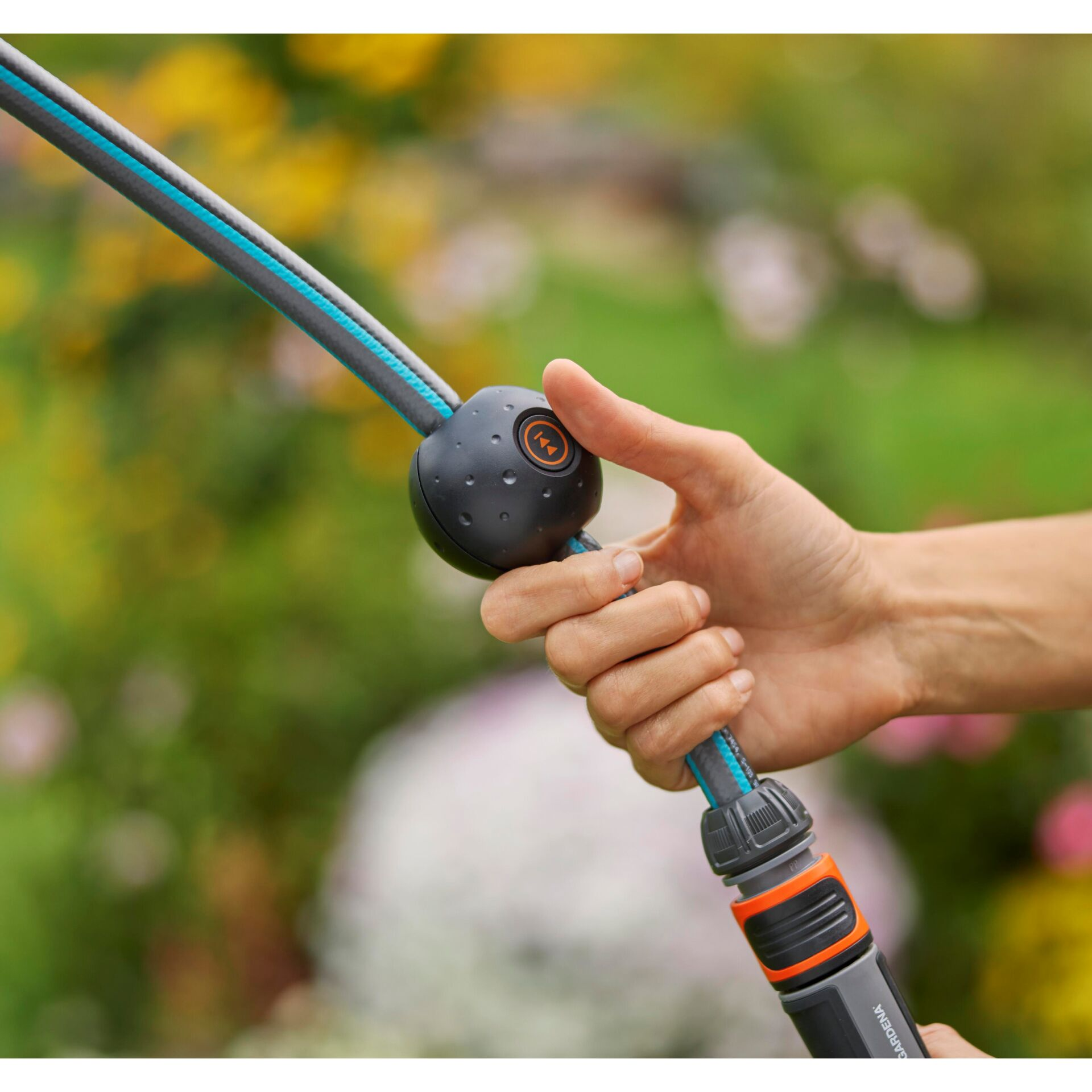 Hand hält ein Gartenschlauch-Griffstück mit einem Knopf und zwei blauen Streifen.