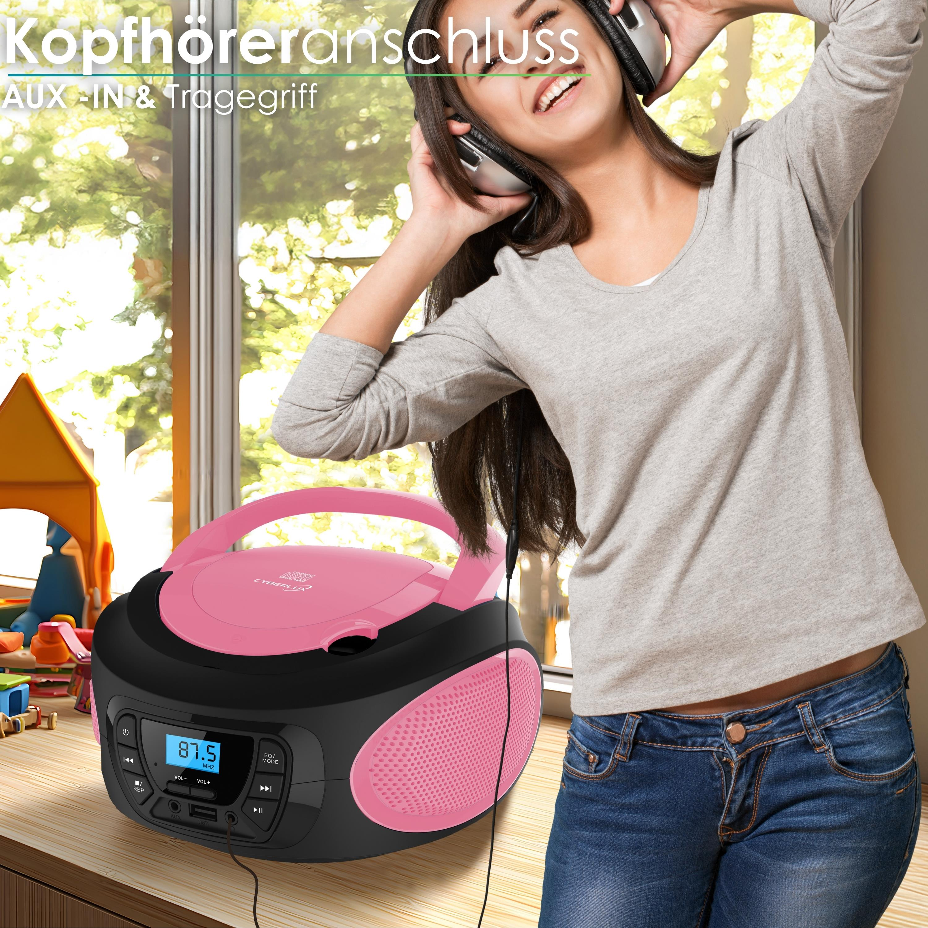 Eine Frau mit Kopfhörern hört Musik von einem pinken CD-Player. Kinderzimmer-Deko im Hintergrund.