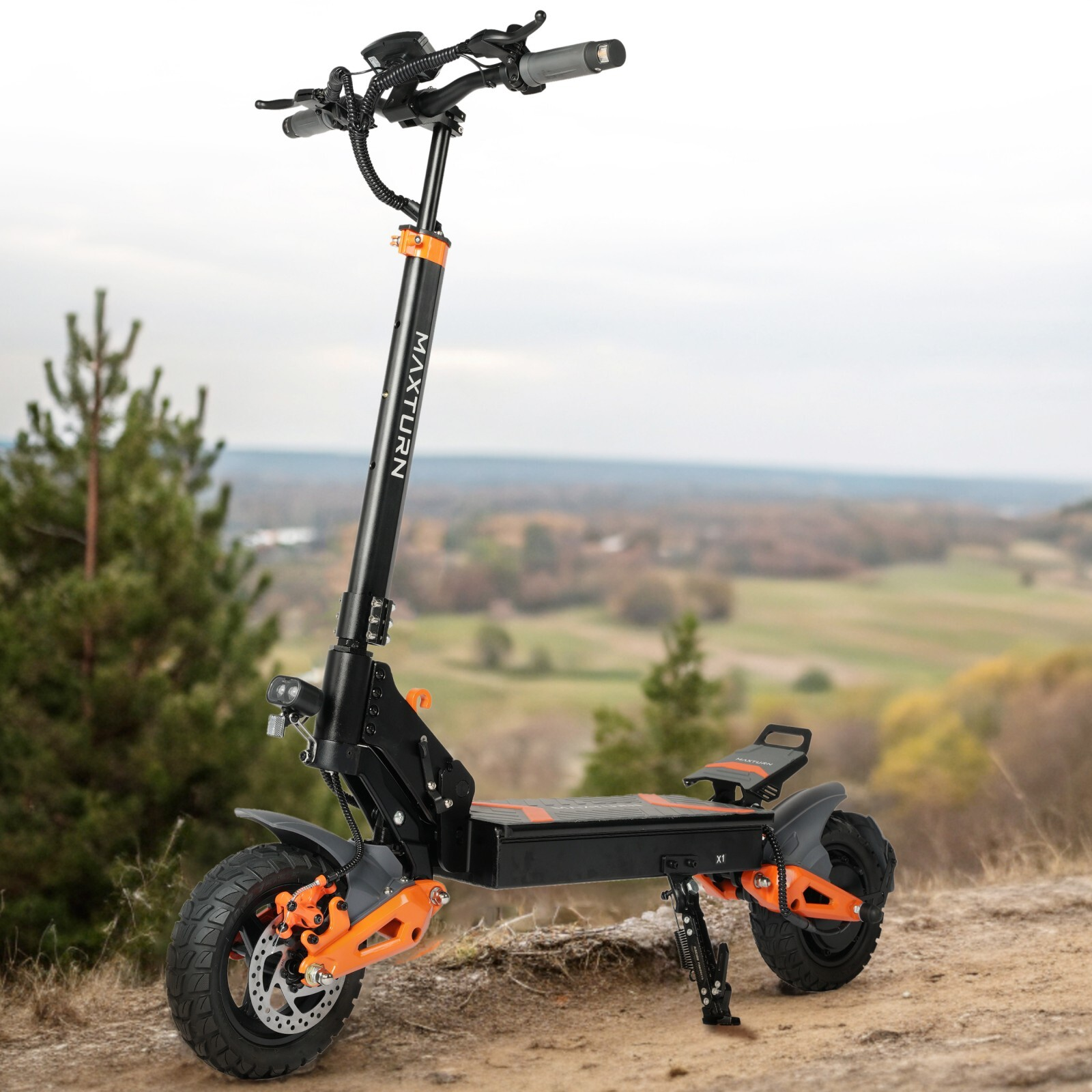 Czarna hulajnoga elektryczna z pomarańczowymi akcentami stoi na zewnątrz na nierównym terenie.