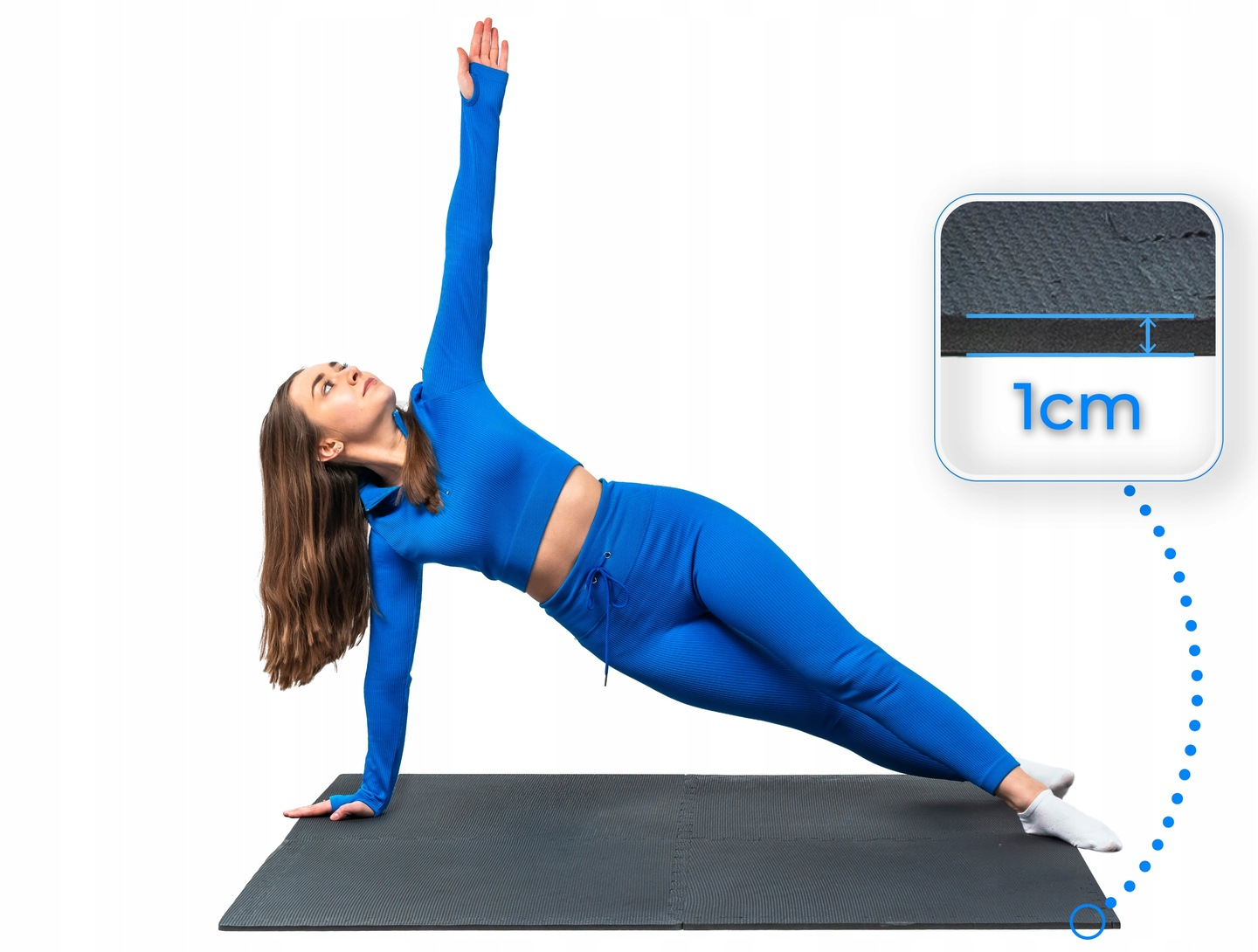 Kobieta w niebieskim stroju sportowym wykonuje boczną deskę na macie. Grubość 1 cm.