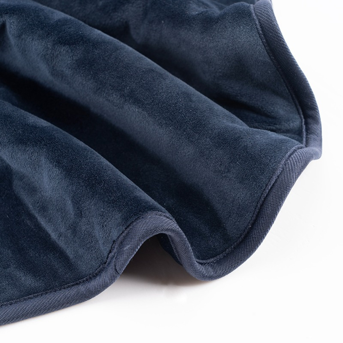 Granatowy koc z miękką fakturą i szytymi krawędziami.