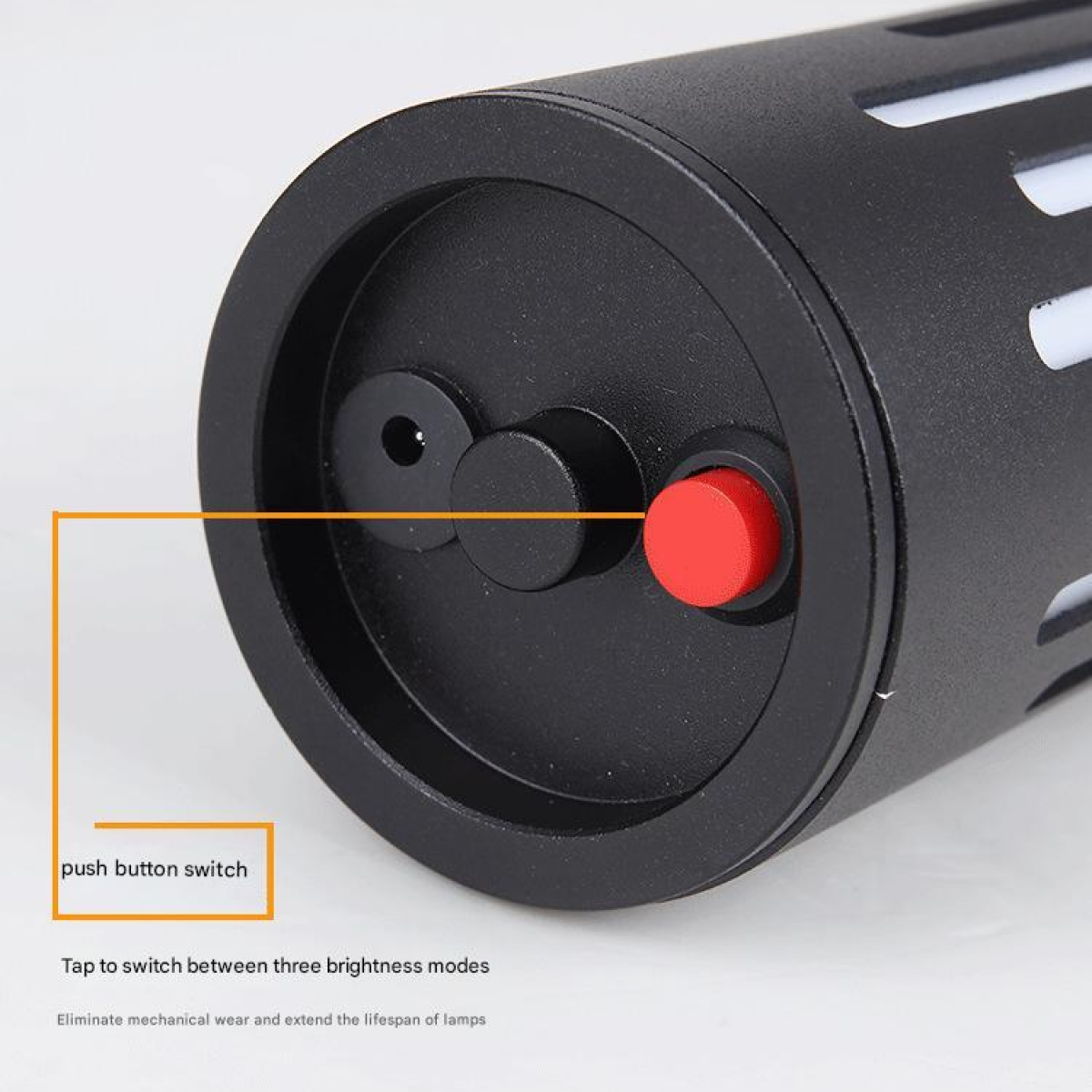 Schwarzer Zylinder mit rotem Knopf und Beschriftung 'push button switch'.