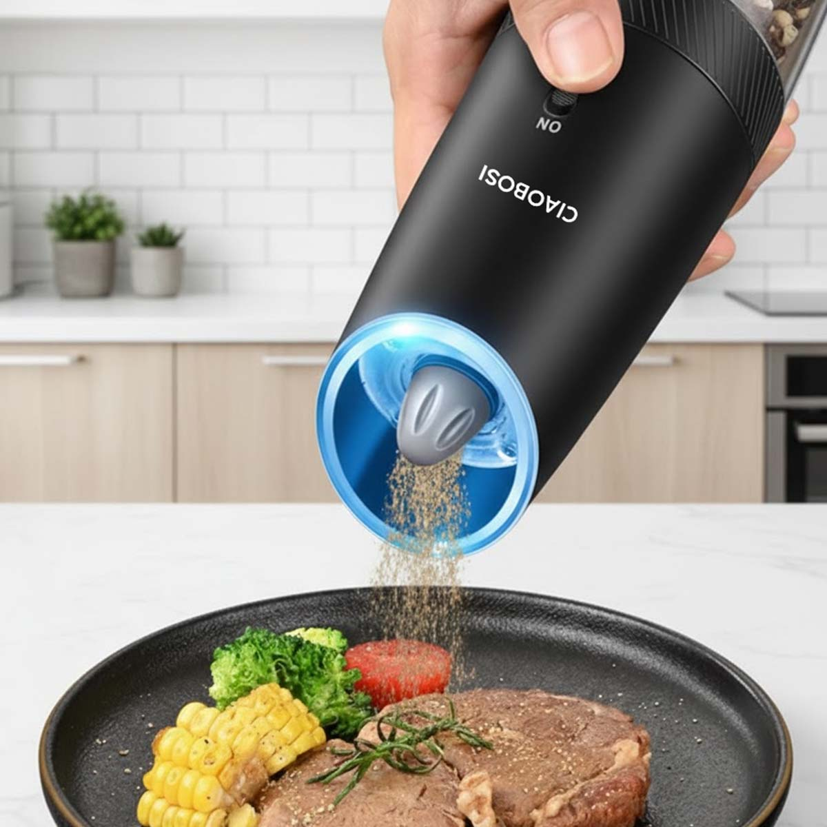 Eine schwarze elektrische Pfeffermühle gibt Gewürz auf ein Steak mit Mais, Brokkoli und Tomaten.