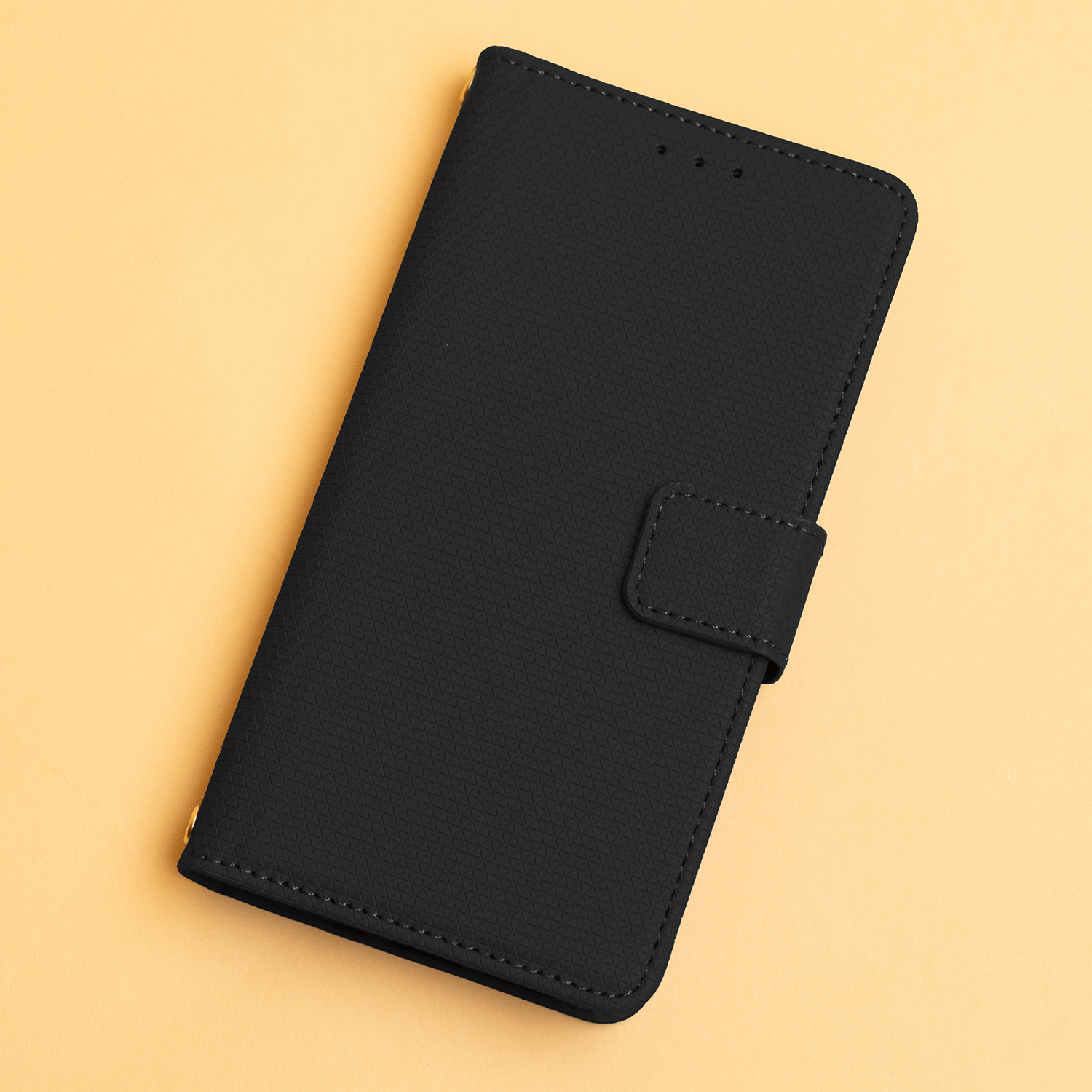 Ein schwarzes Handycover liegt auf einem hellgelben Untergrund.