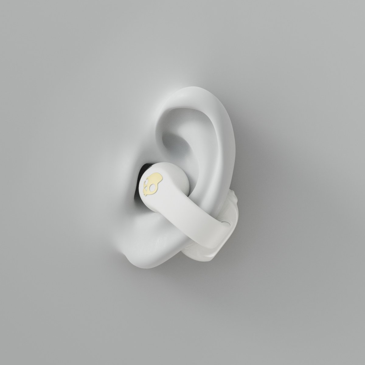 Un auricolare bianco con logo teschio dorato in un orecchio bianco.