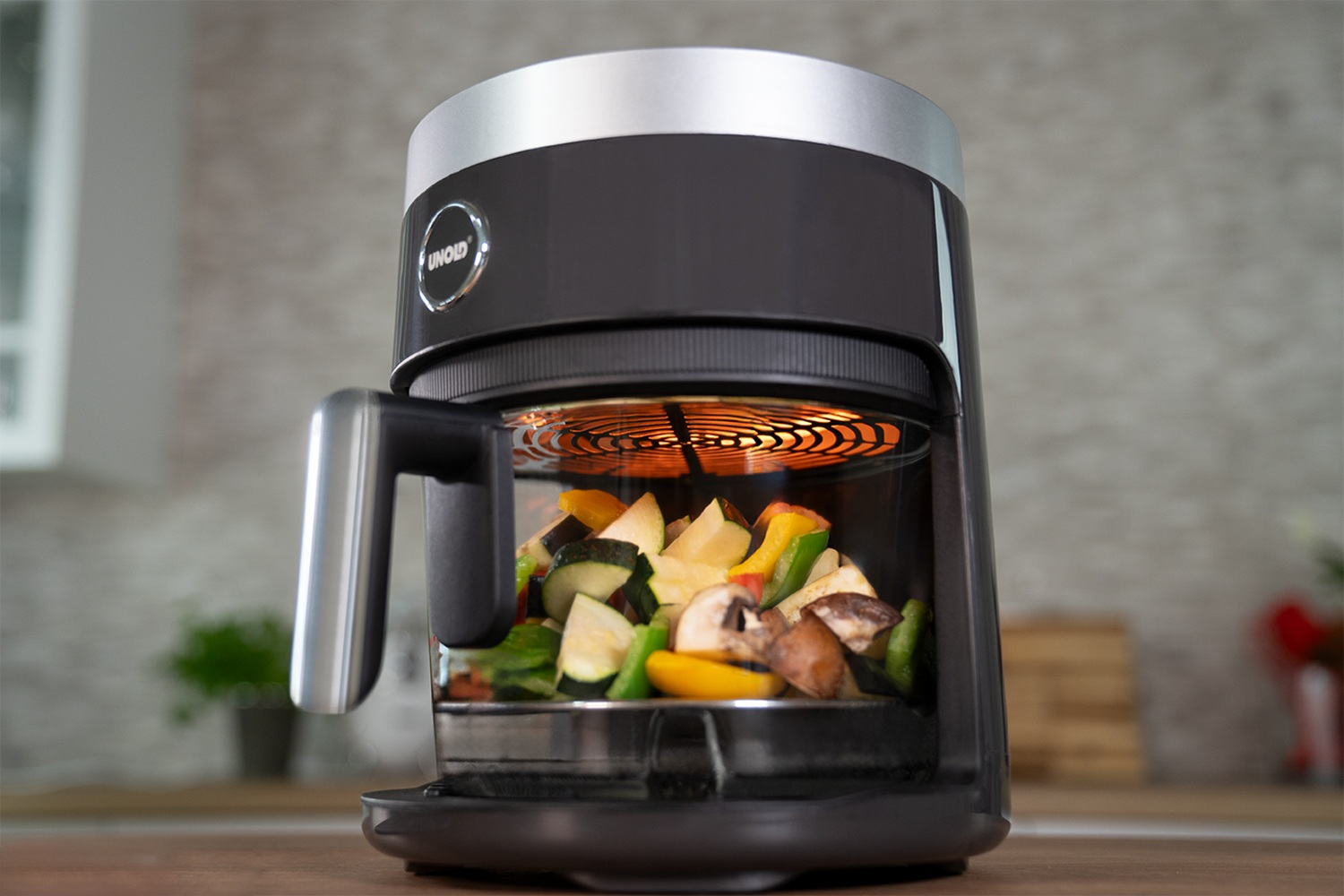 Czarna frytkownica beztłuszczowa z warzywami i grzałką na górze.