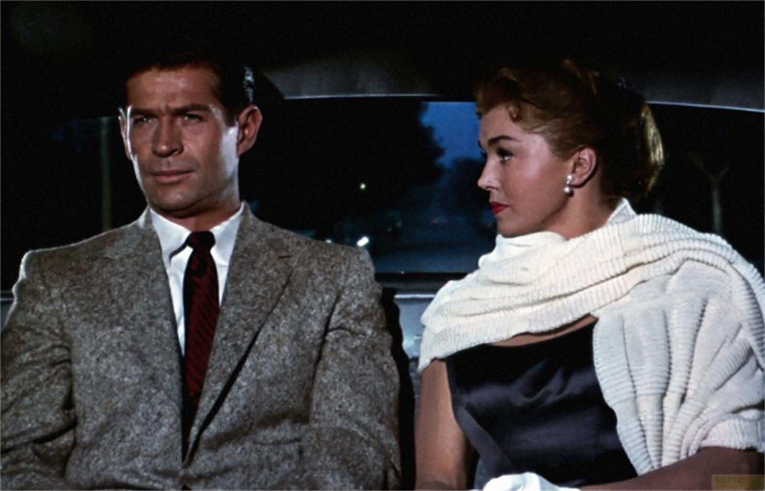 Un uomo in abito e una donna in vestito con scialle siedono in auto.