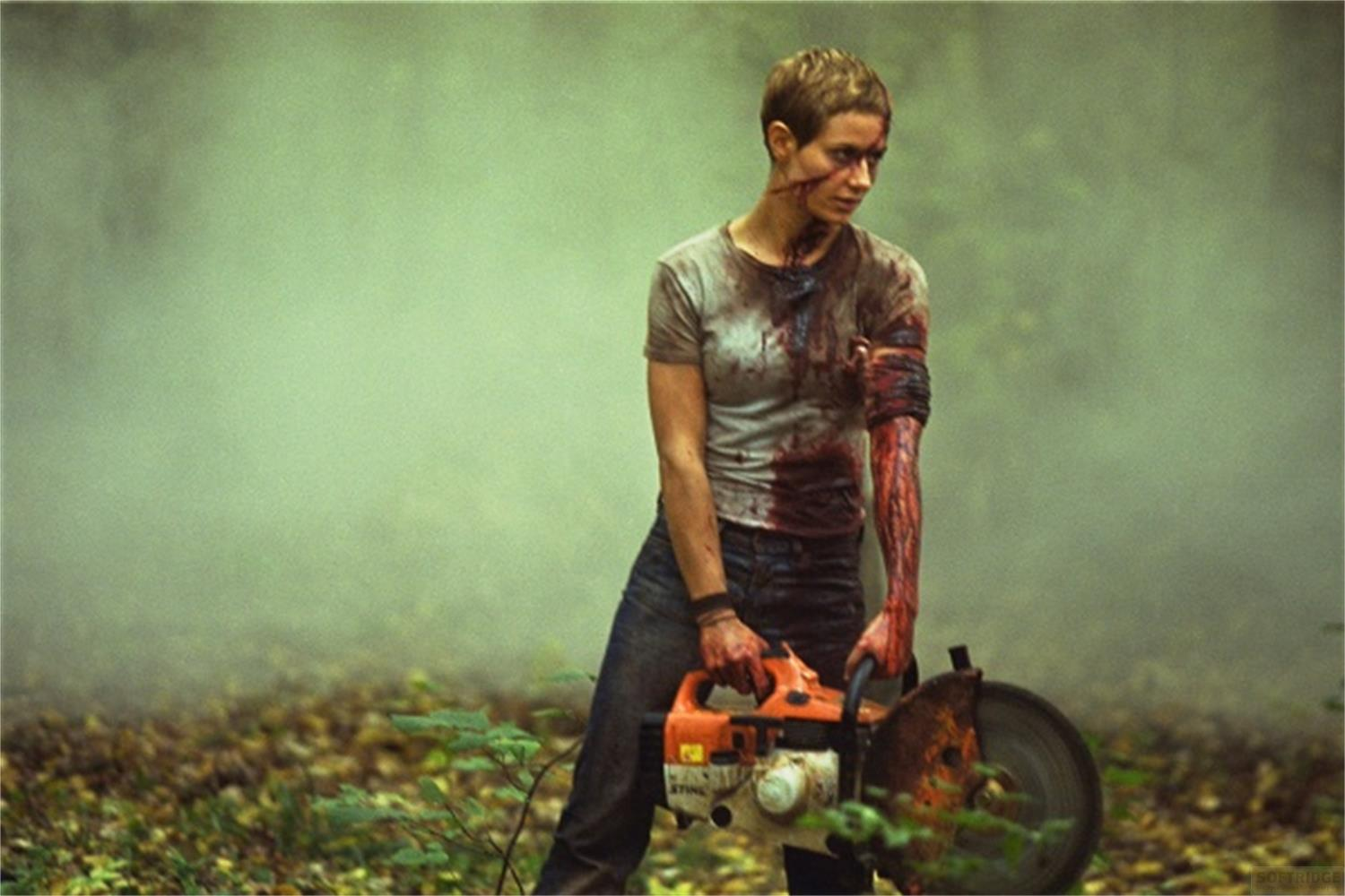 Donna ferita con motosega in una foresta, coperta di sangue.
