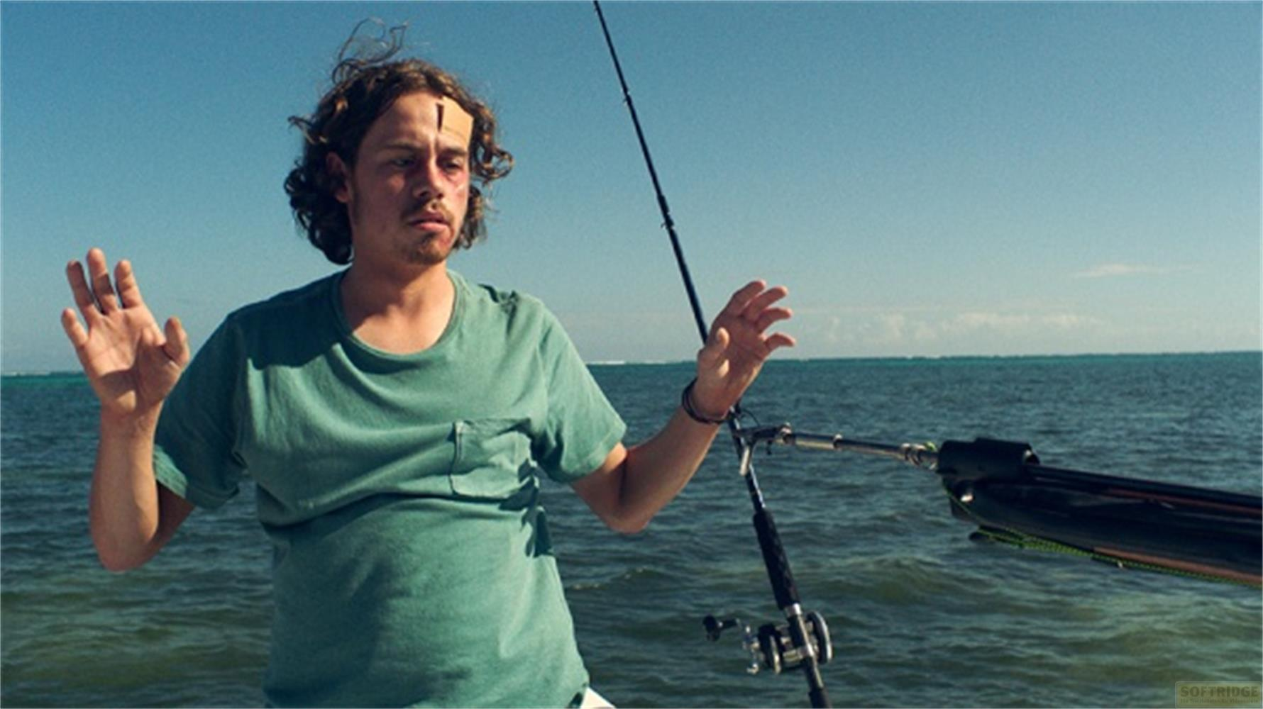 Un uomo con una benda sulla fronte sta su una barca in mare.