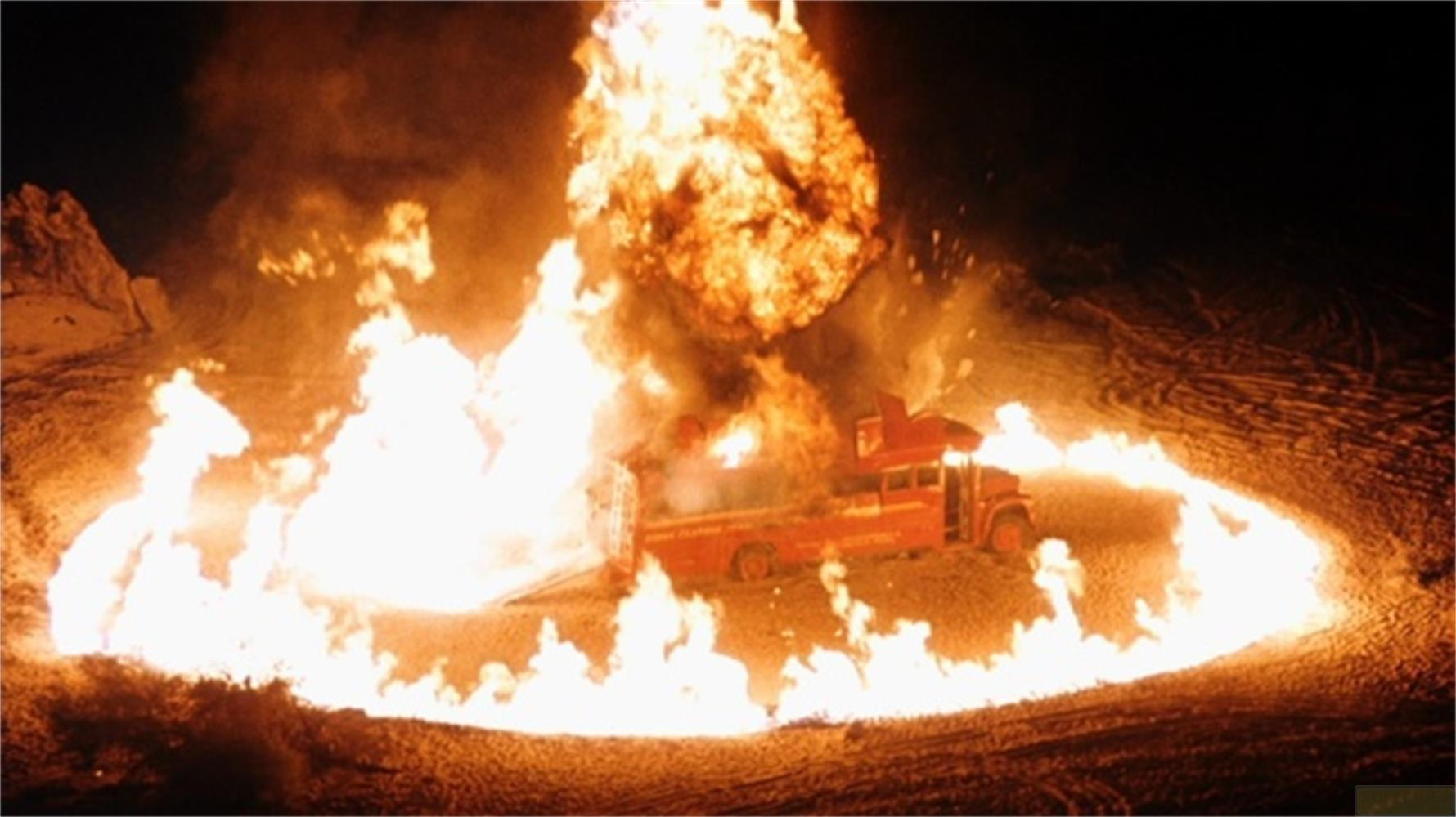 Un autobus rosso esplode in fiamme in un paesaggio innevato di notte.