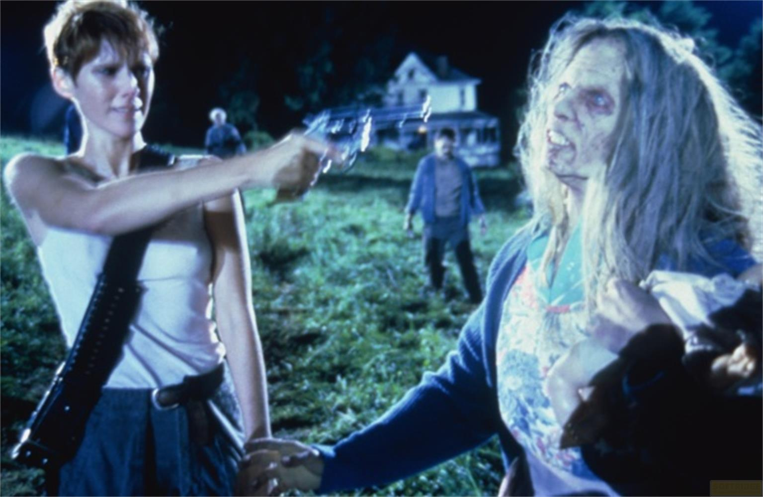 Donna punta pistola a zombie davanti casa. Due zombie sullo sfondo.