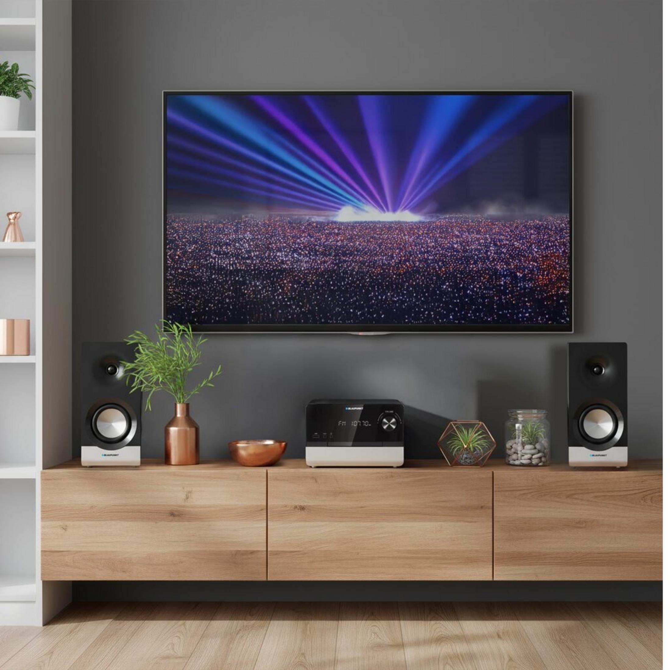 Una TV mostra un concerto con raggi di luce su una folla.