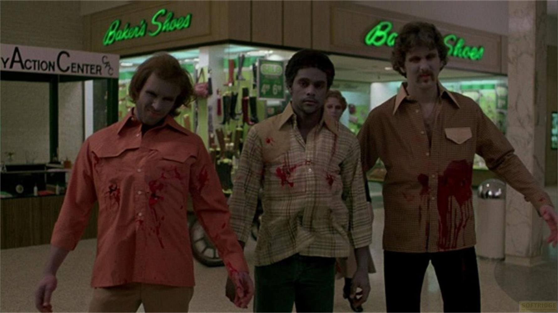 Tre uomini con macchie di sangue e trucco da zombie in un centro commerciale.