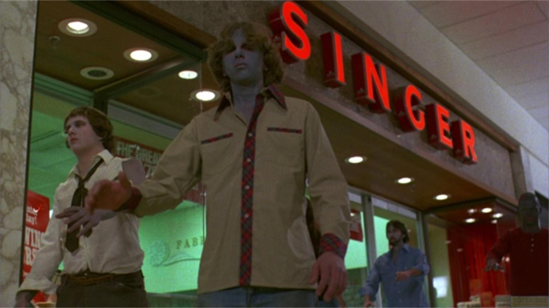 Zombie in un centro commerciale davanti a un'insegna Singer.