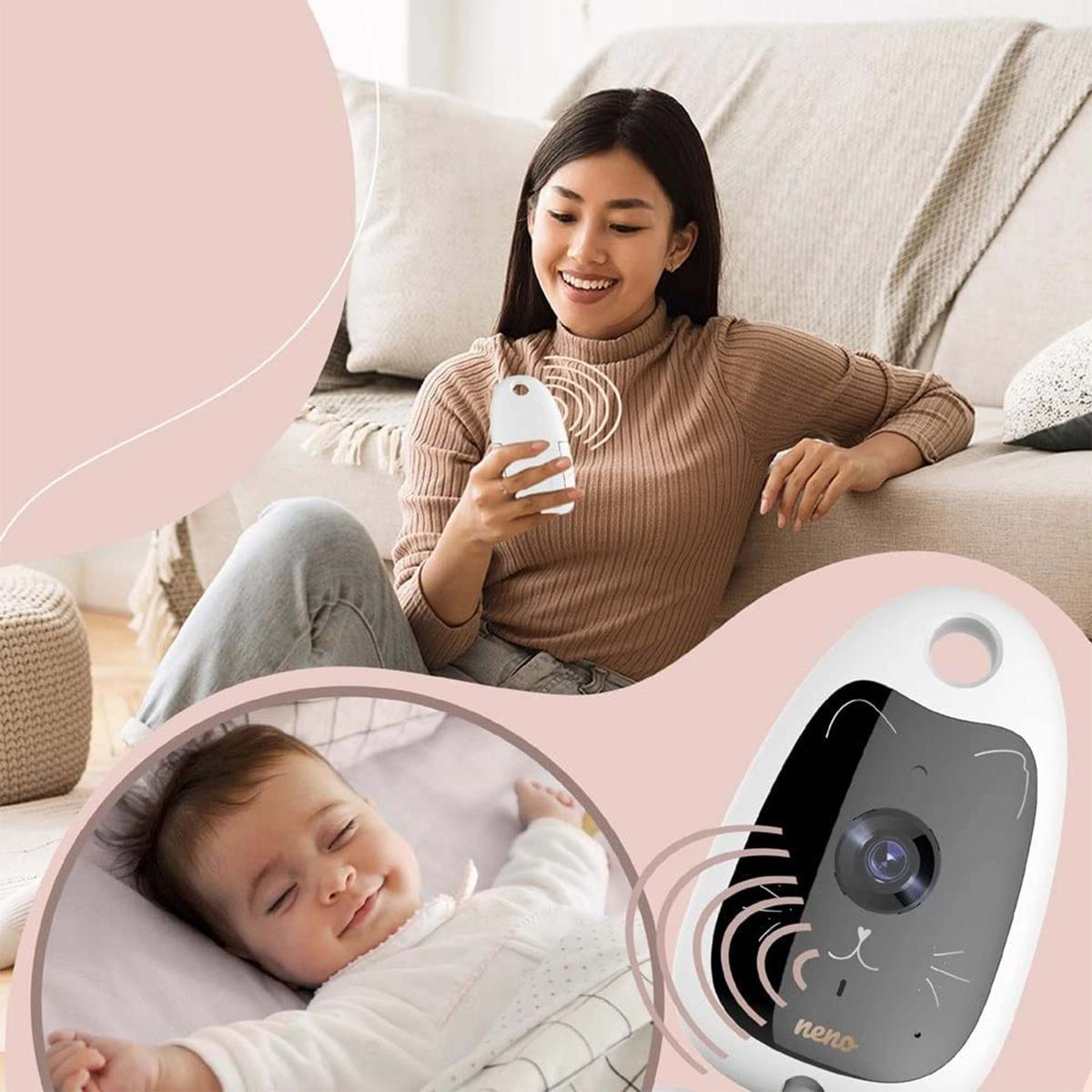 Donna tiene baby monitor; neonato dorme in culla. Telecamera baby monitor in primo piano.