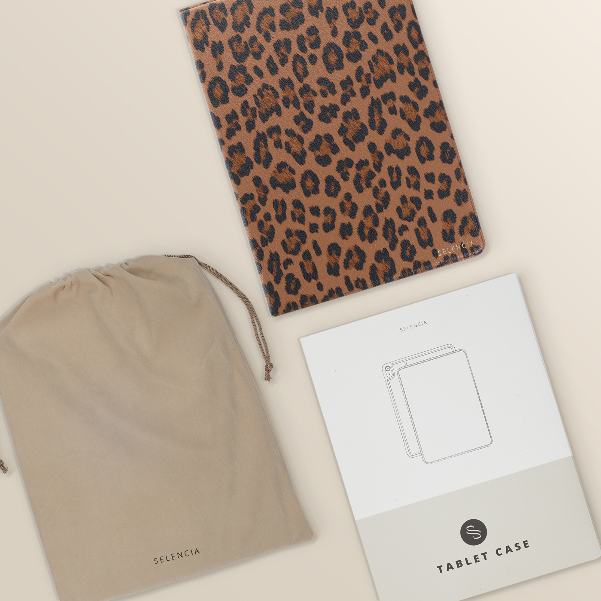 A leopard print tablet case, a pouch, and instructions lie on a light surface.