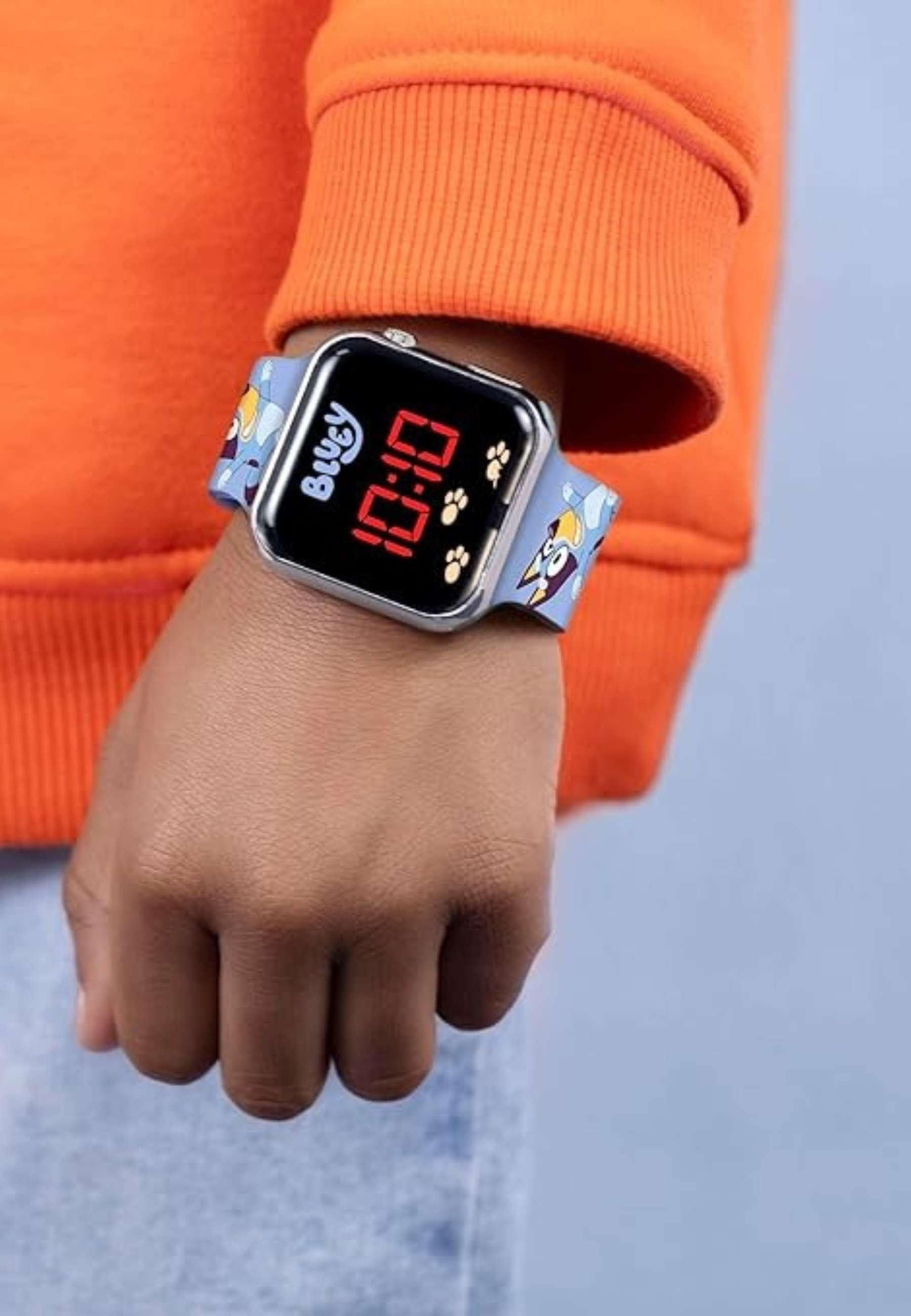 Ein Kind trägt eine orangefarbene Kapuzenjacke und eine Bluey-Uhr mit Digitalanzeige.