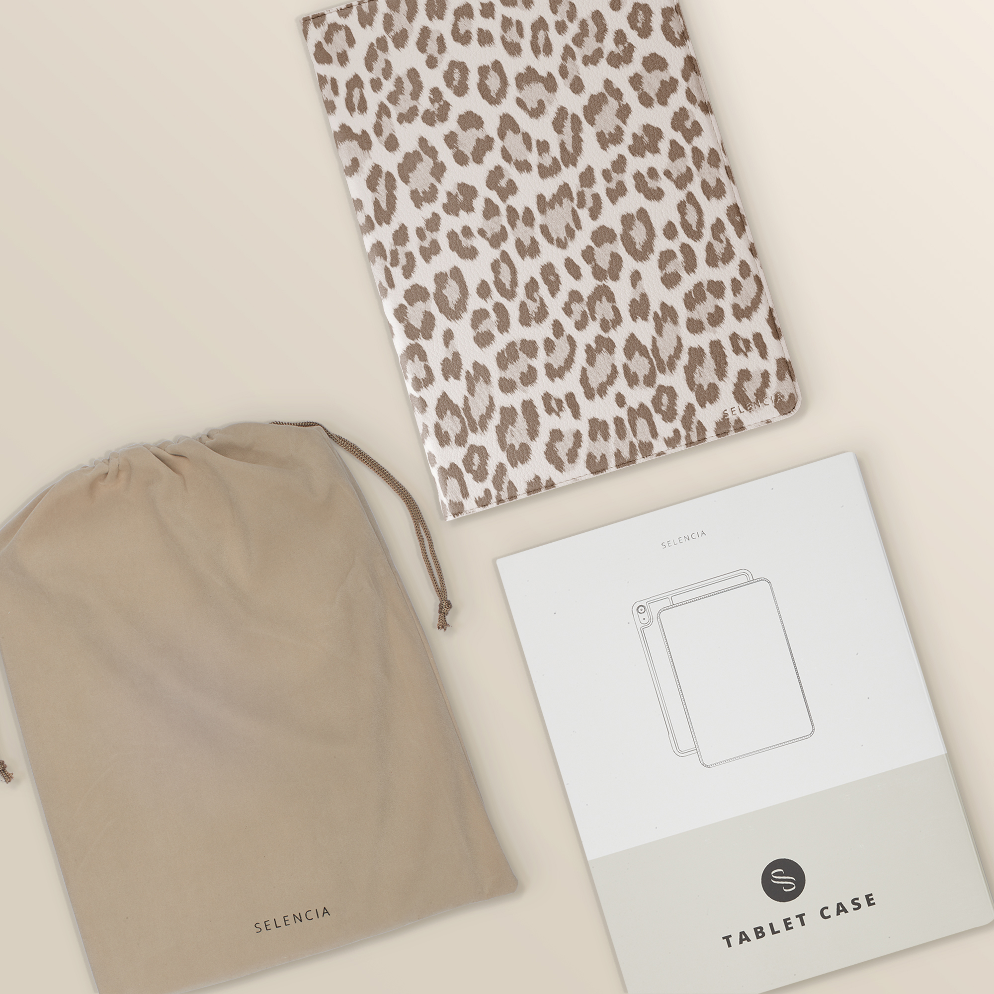 A leopard print tablet case, a beige dust bag, and a manual lie side by side.