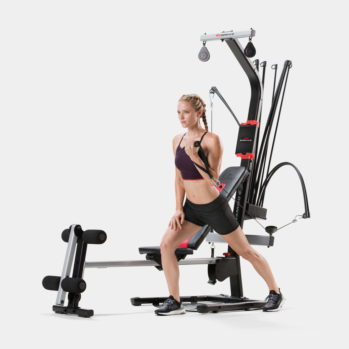 Una mujer se ejercita usando una máquina de fitness con poleas.