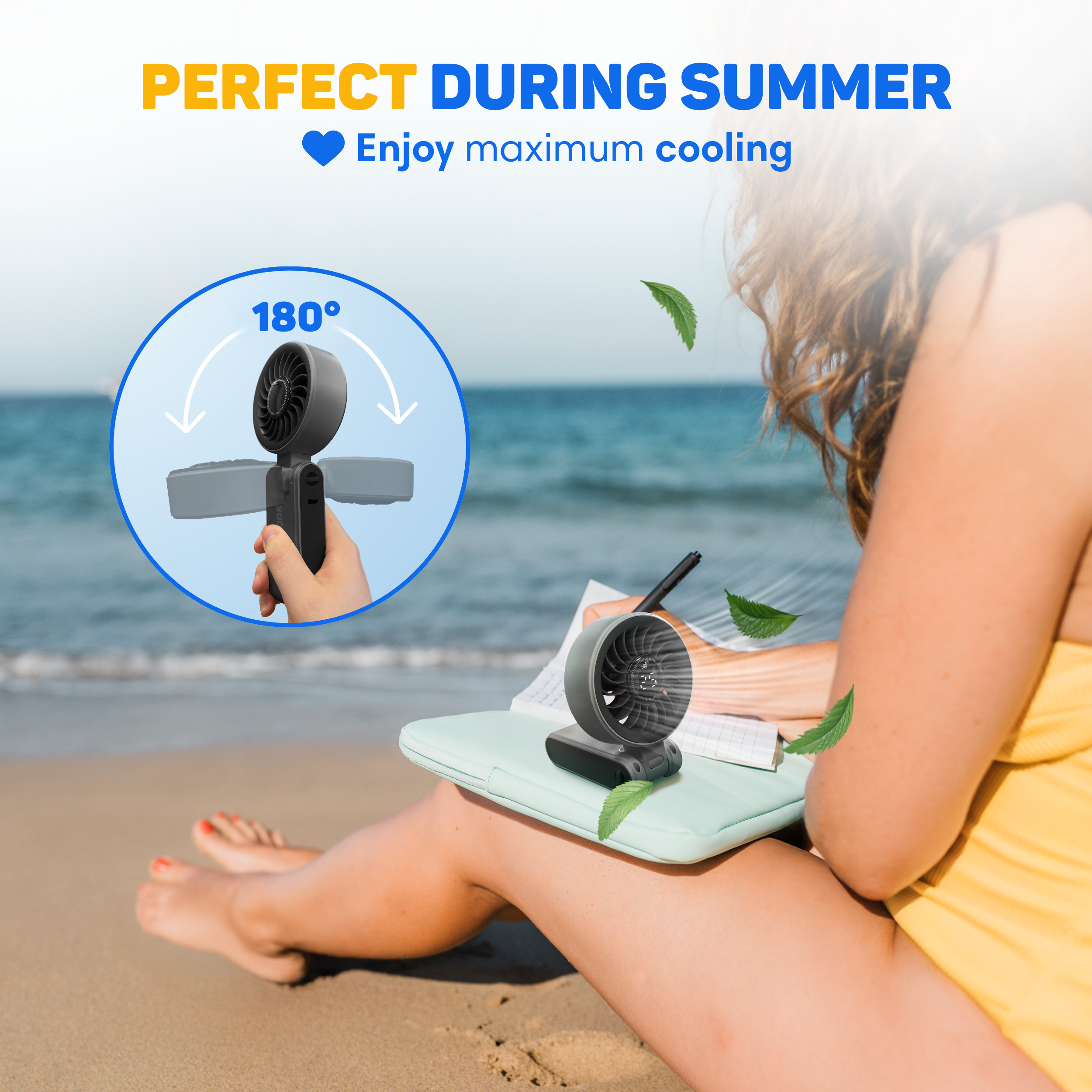 A portable fan on a laptop at the beach, a person is writing.