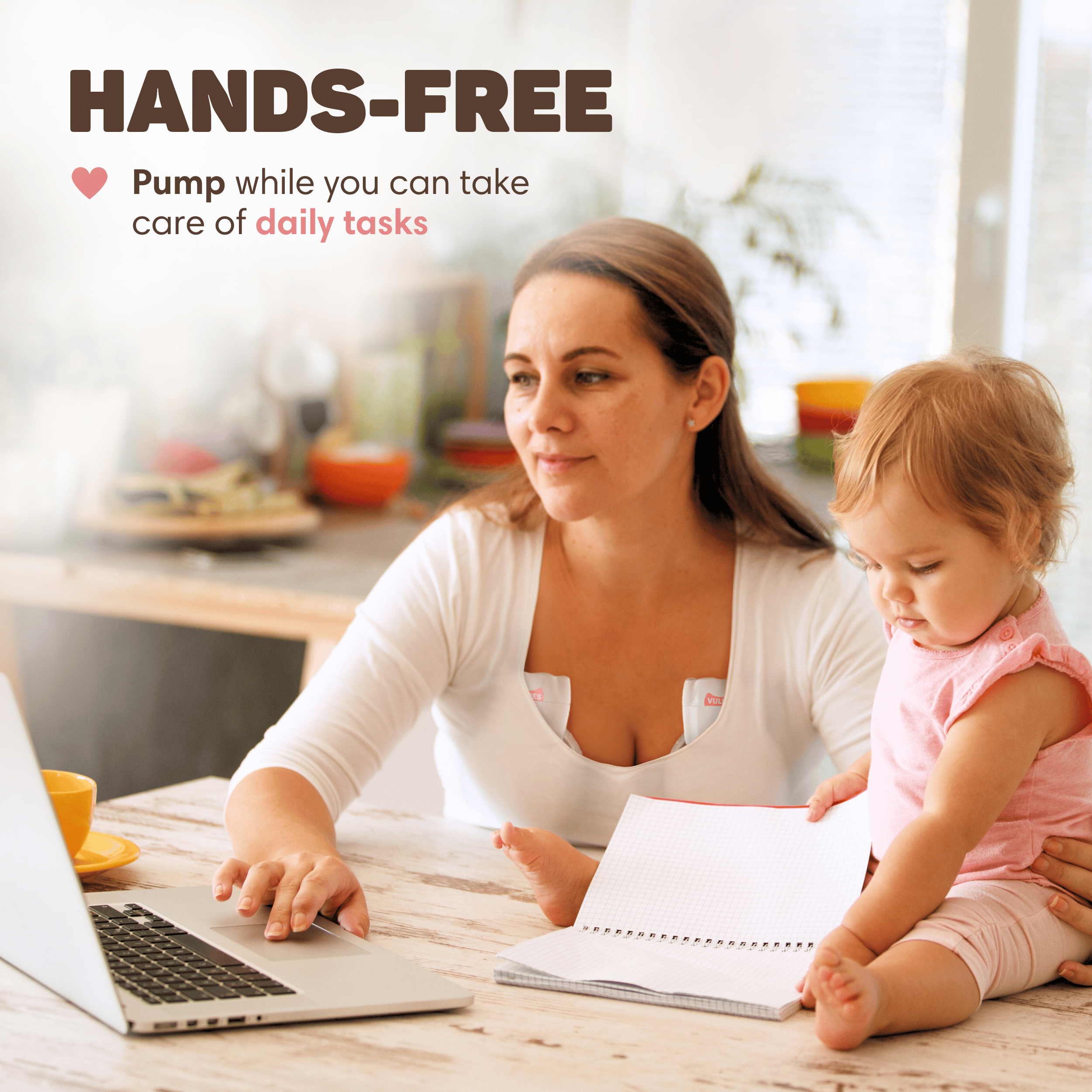 Eine Frau benutzt eine Freisprech-Milchpumpe, während sie auf einem Laptop tippt und ihr Baby im Arm hält.