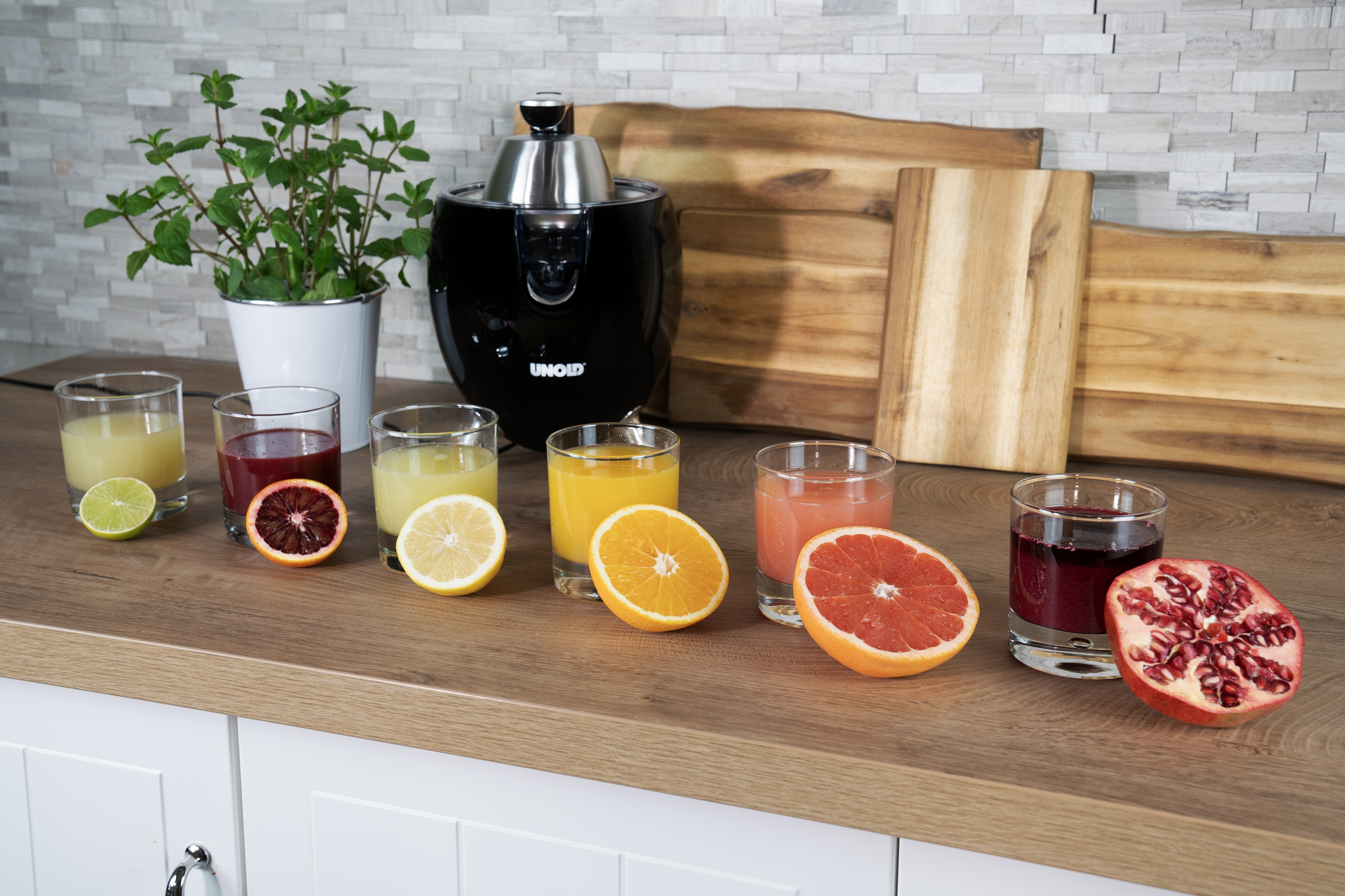 Ein Entsafter mit Gläsern Saft und Früchten auf einer Holzoberfläche.