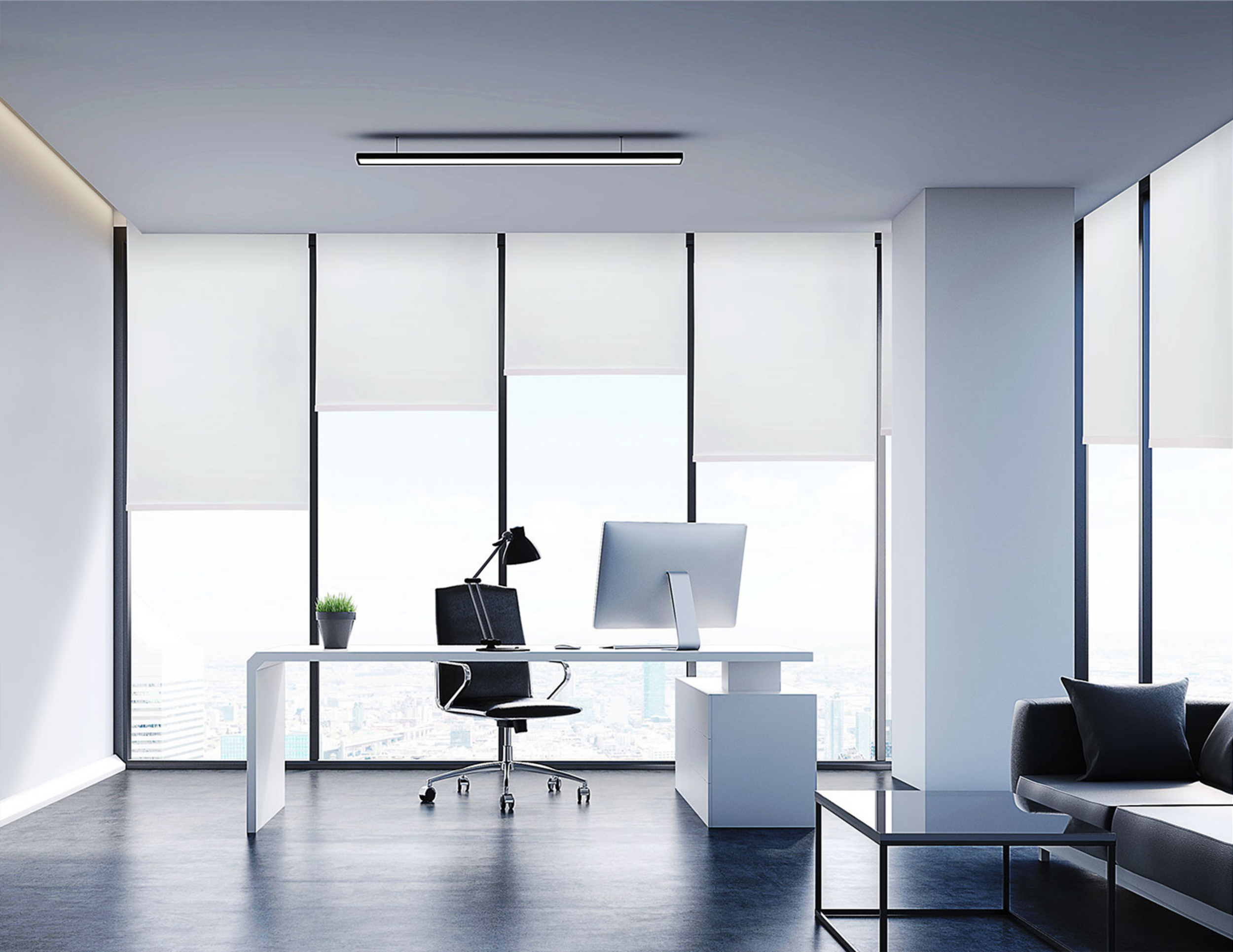 Nowoczesne biuro z biurkiem, komputerem, krzesłem i sofą na pierwszym planie.