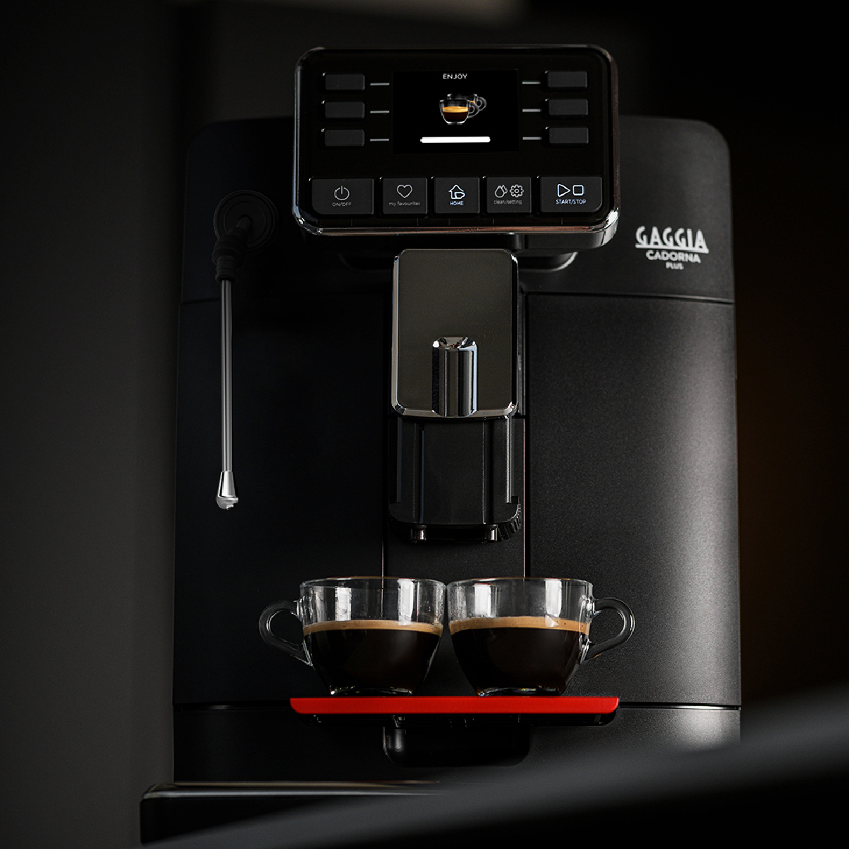 Een zwarte koffiemachine met twee espressokopjes op een rood dienblad.