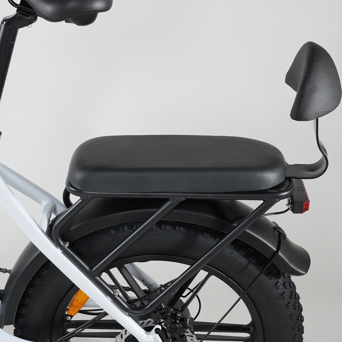 Zbliżenie na bagażnik, siedzenie i oponę roweru elektrycznego.