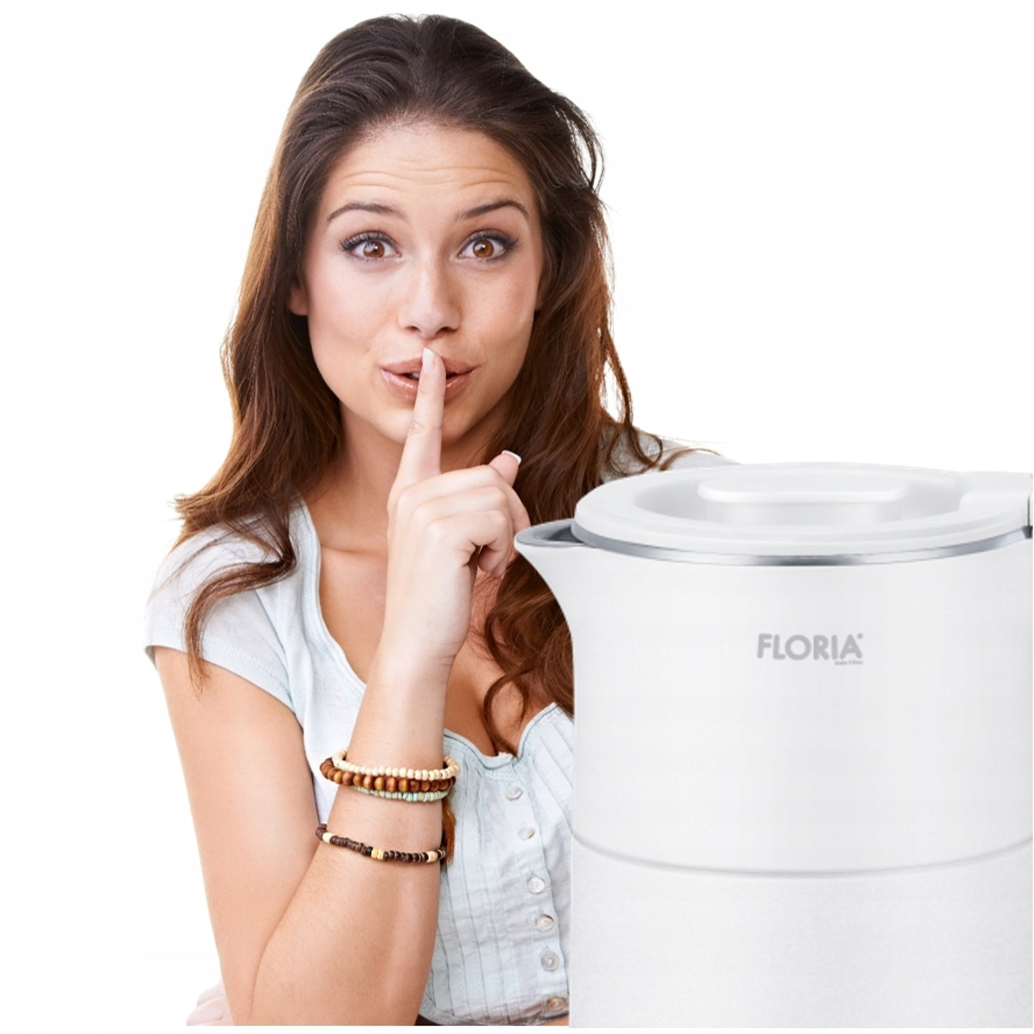 Kobieta kładzie palec na ustach obok białego czajnika.