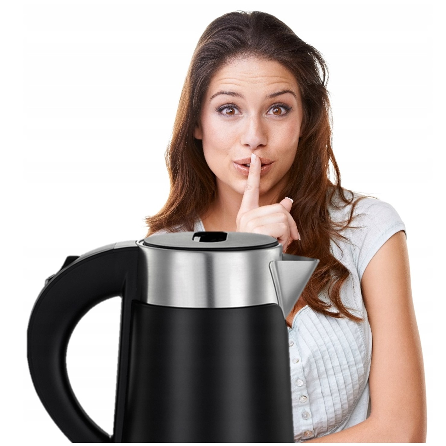 Kobieta z brązowymi włosami wykonuje gest ciszy obok czajnika elektrycznego.