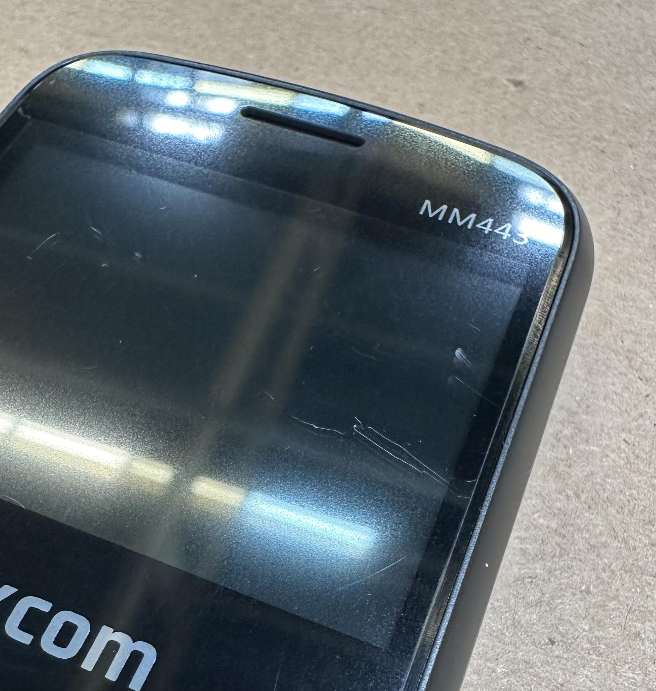 Czarny telefon komórkowy z napisem "MM443" na ekranie.