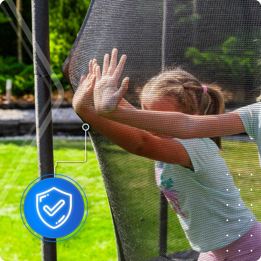 Dziewczynka opiera się o siatkę trampoliny. Niebieska tarcza.