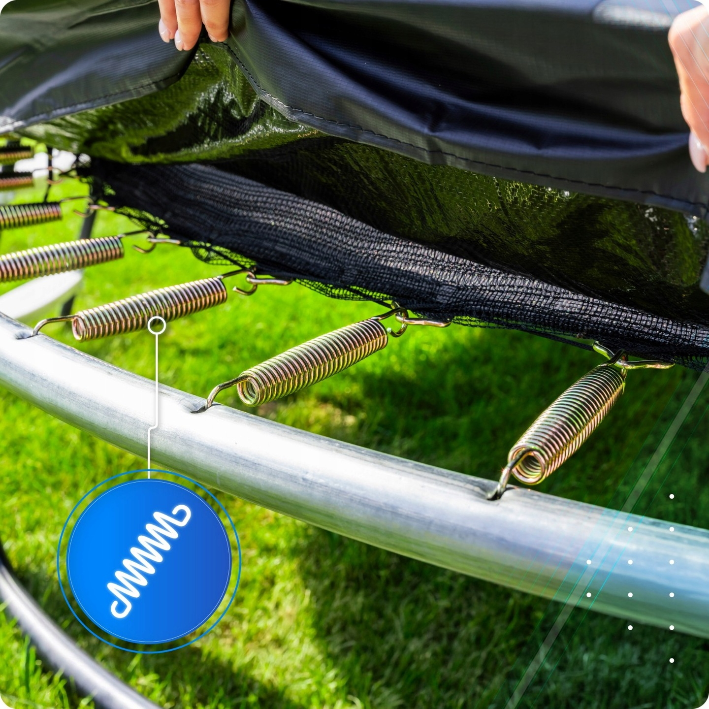 Sprężyny trampoliny przymocowane do metalowej ramy z trawą w tle.