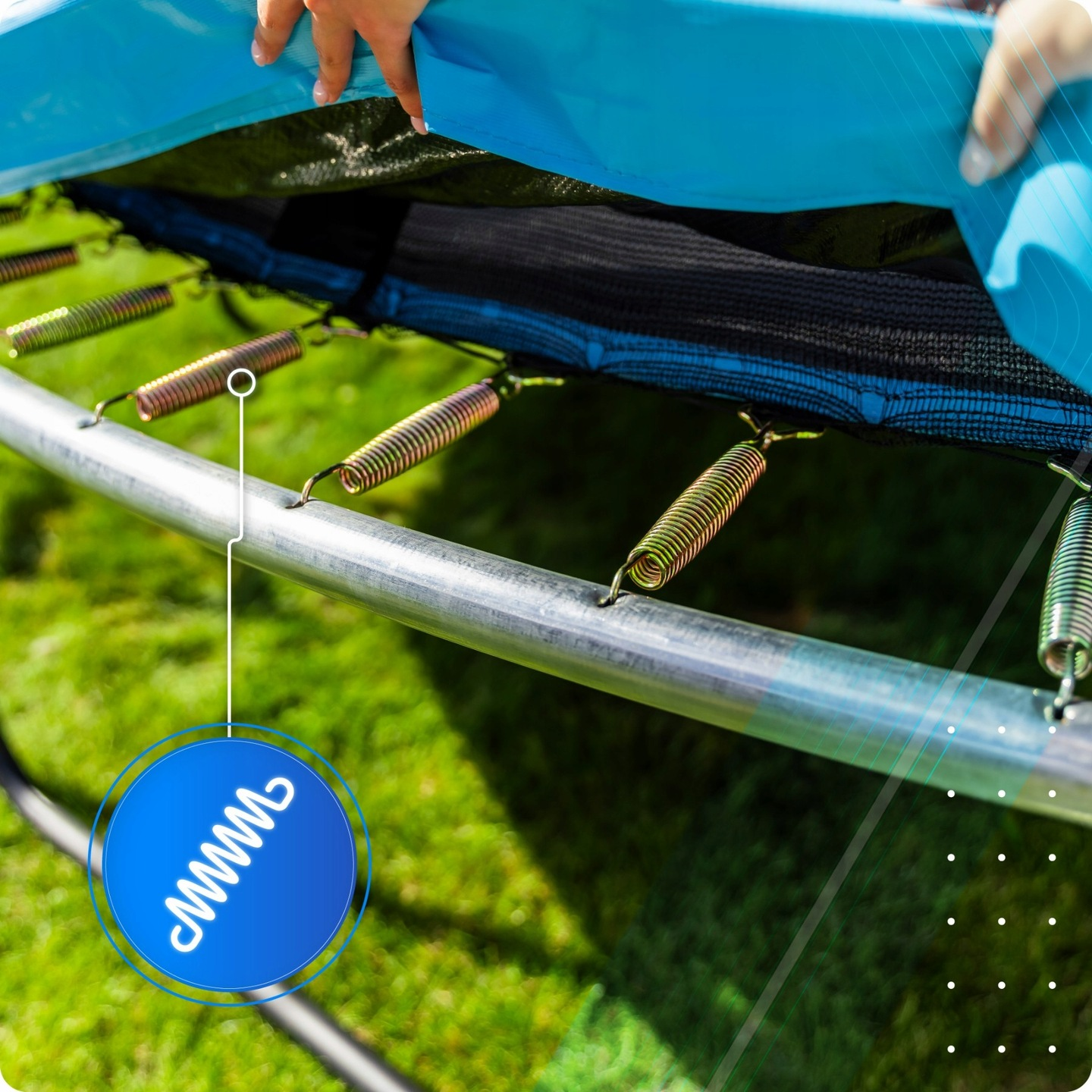 Ręce trzymające niebieską matę trampoliny nad srebrnymi sprężynami.