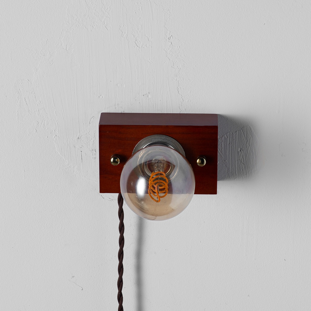 Una lámpara de pared con bombilla Edison sobre viga de madera.