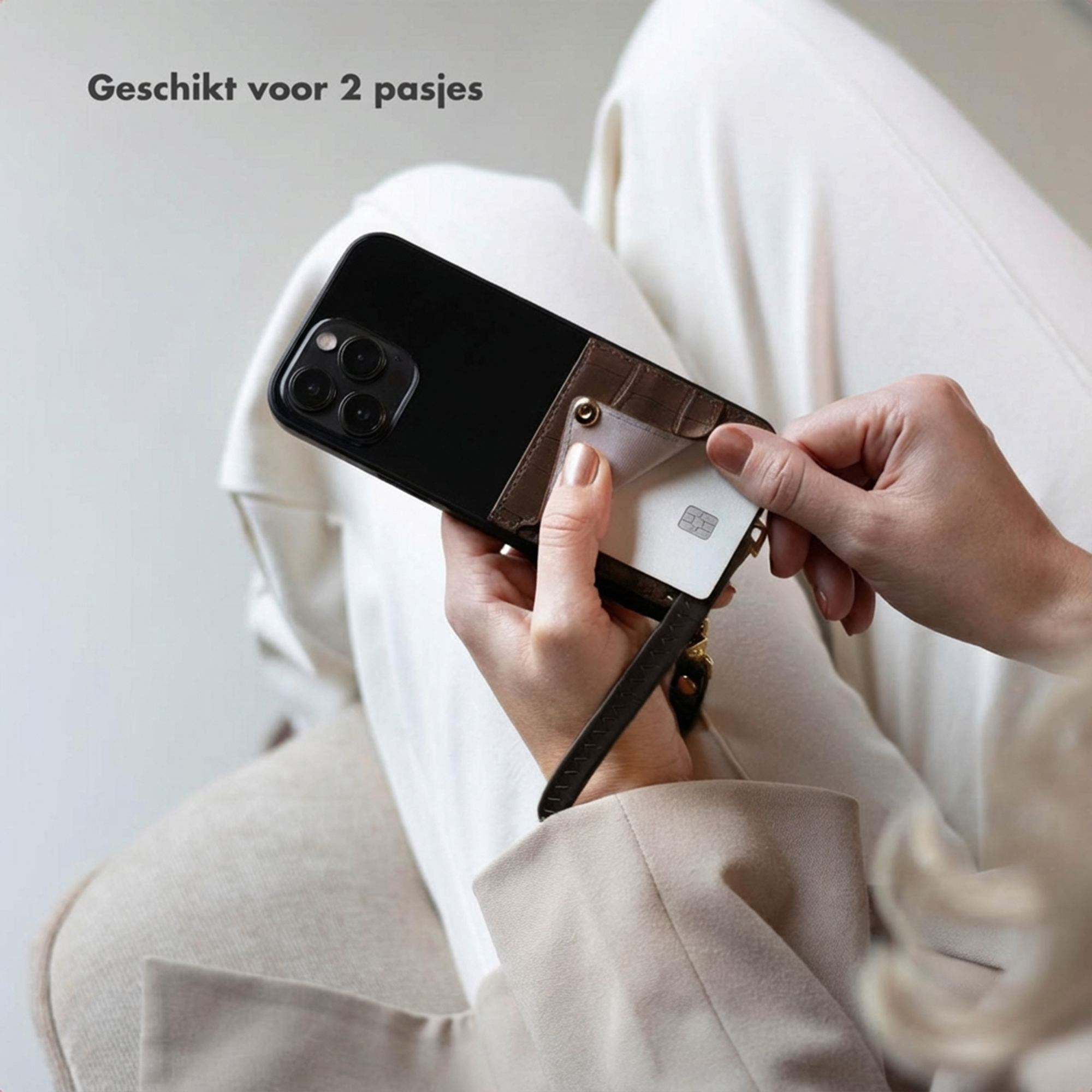 Een hand steekt een witte kaart in een bruine telefoonhoes.