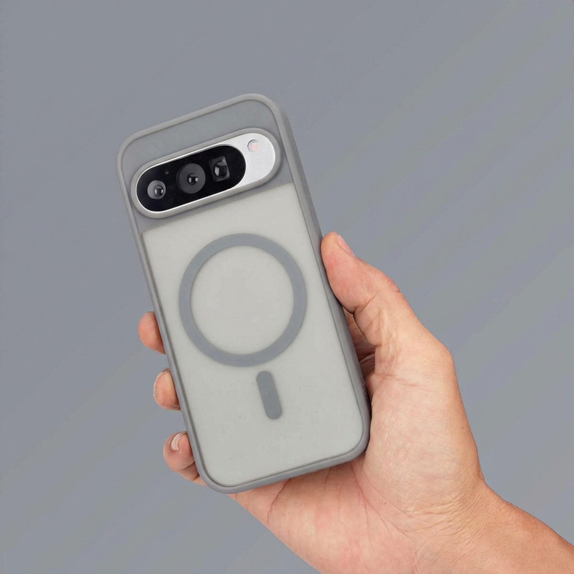 Grijze telefoonhoes met MagSafe-ring in de hand gehouden.