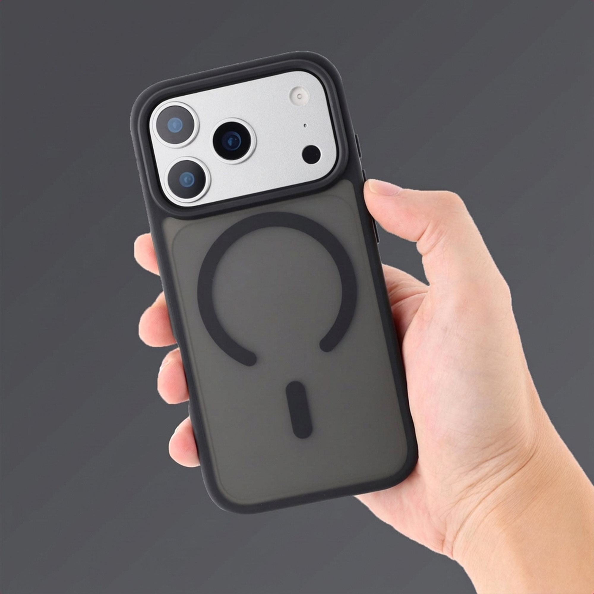 Hand houdt zwarte telefoon met drie camera's en MagSafe cirkel vast.