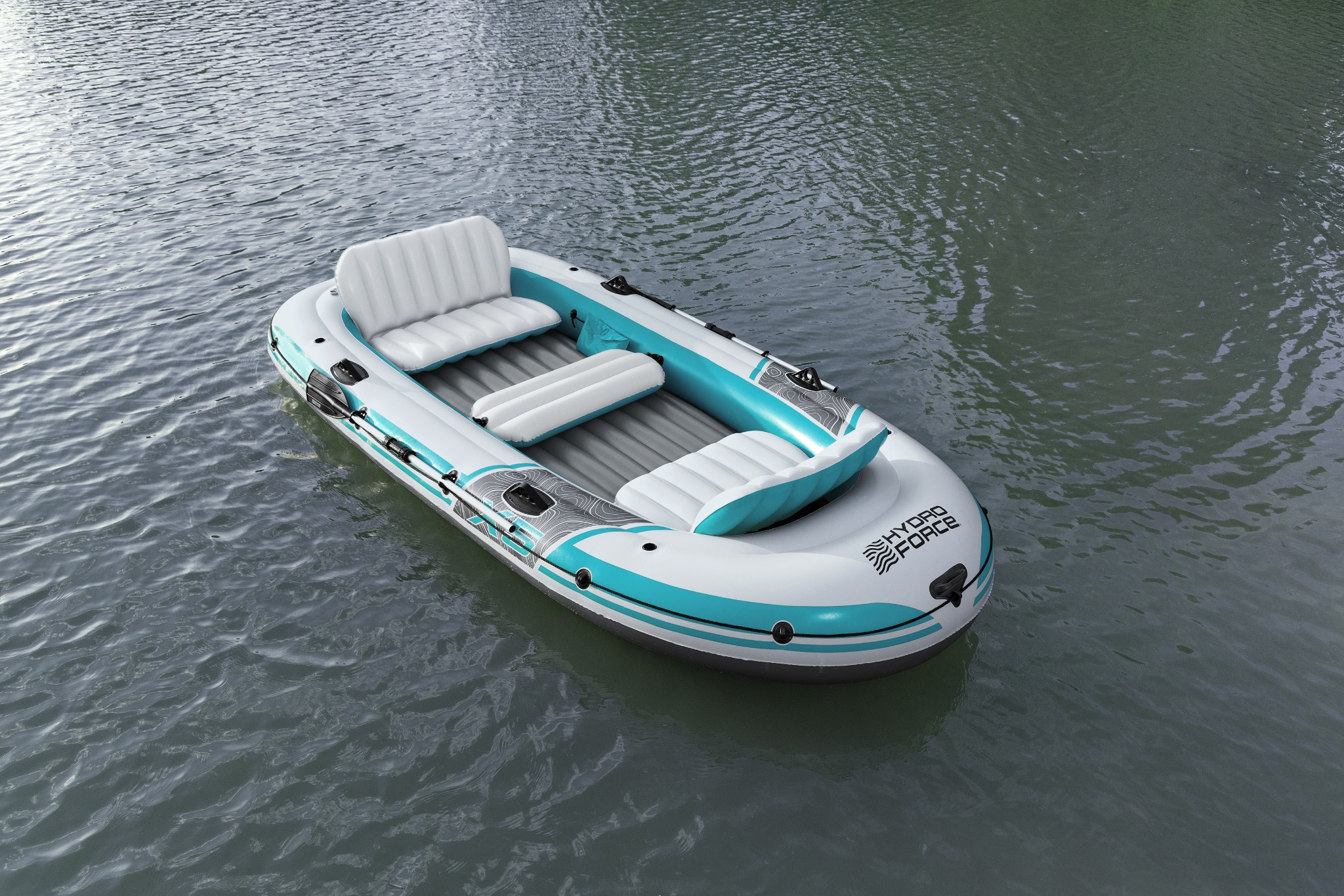 Ein aufblasbares Boot mit weißen und türkisfarbenen Sitzen auf ruhigem Wasser.