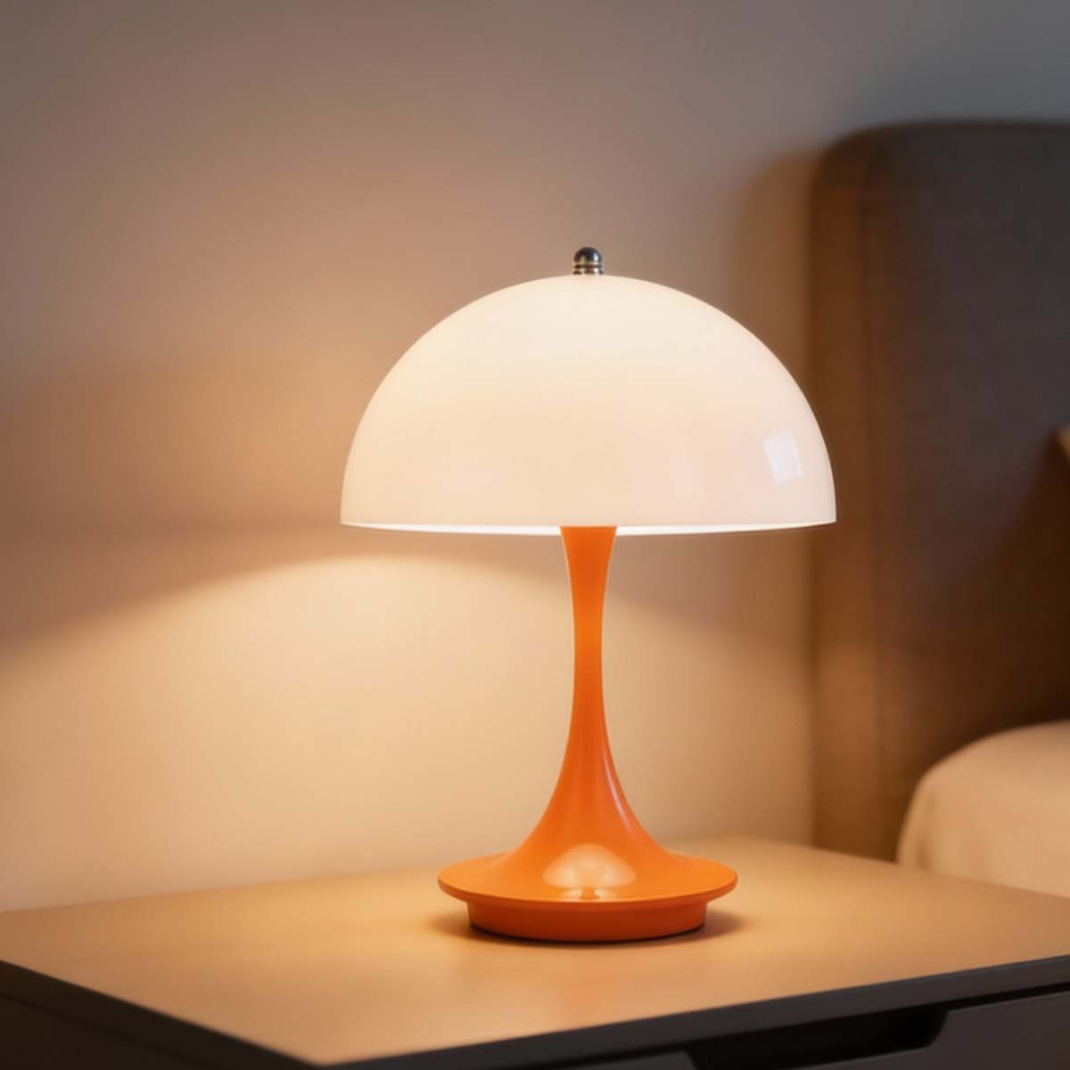 Una lámpara naranja con pantalla blanca sobre una mesita de noche.