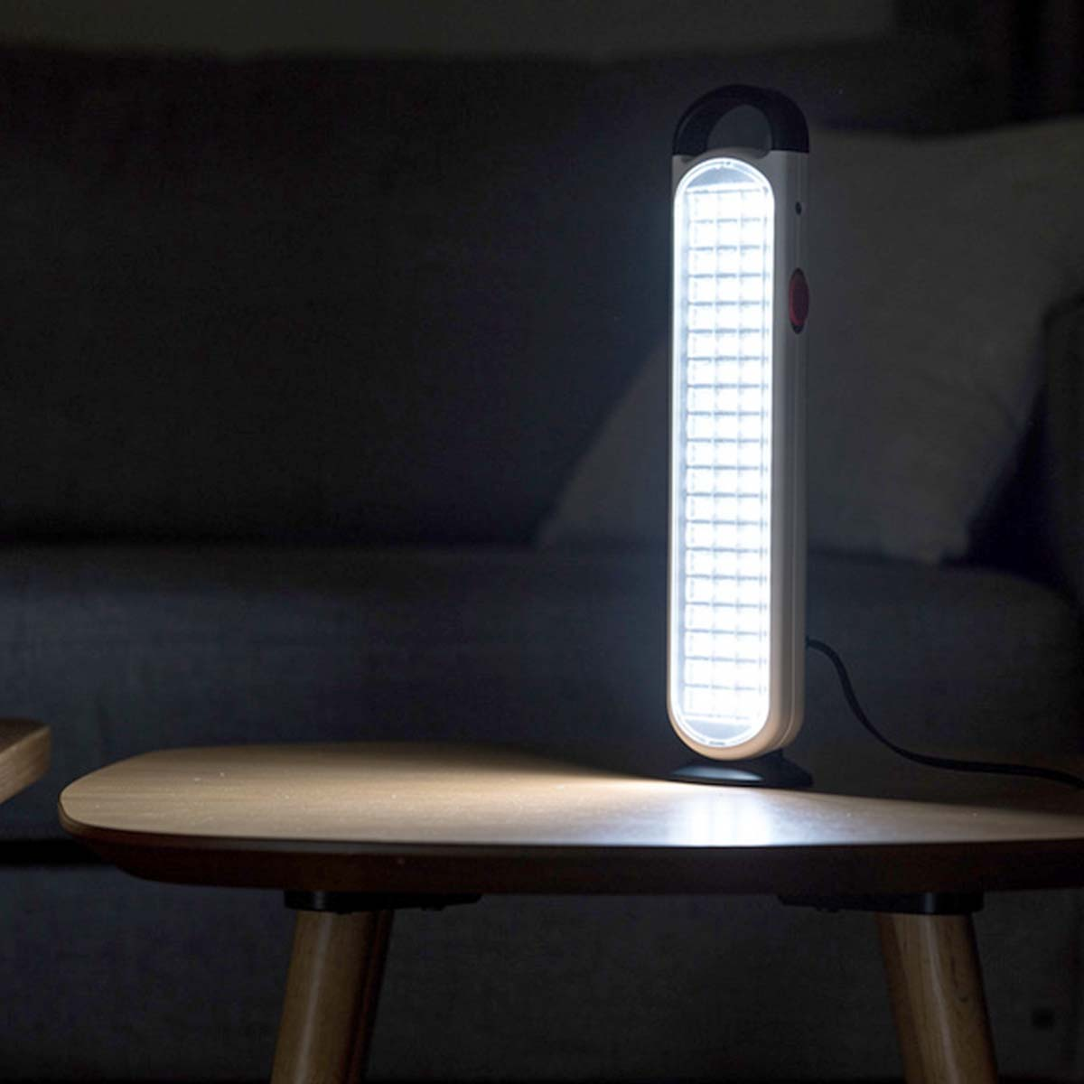 Eine helle LED-Lampe steht auf einem Holztisch im Dunkeln.