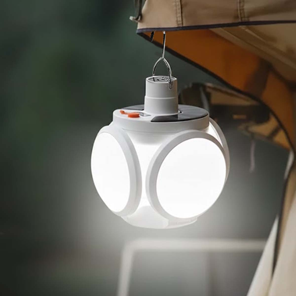 Una linterna blanca en forma de cubo con lados iluminados, colgada de un gancho bajo una tienda.
