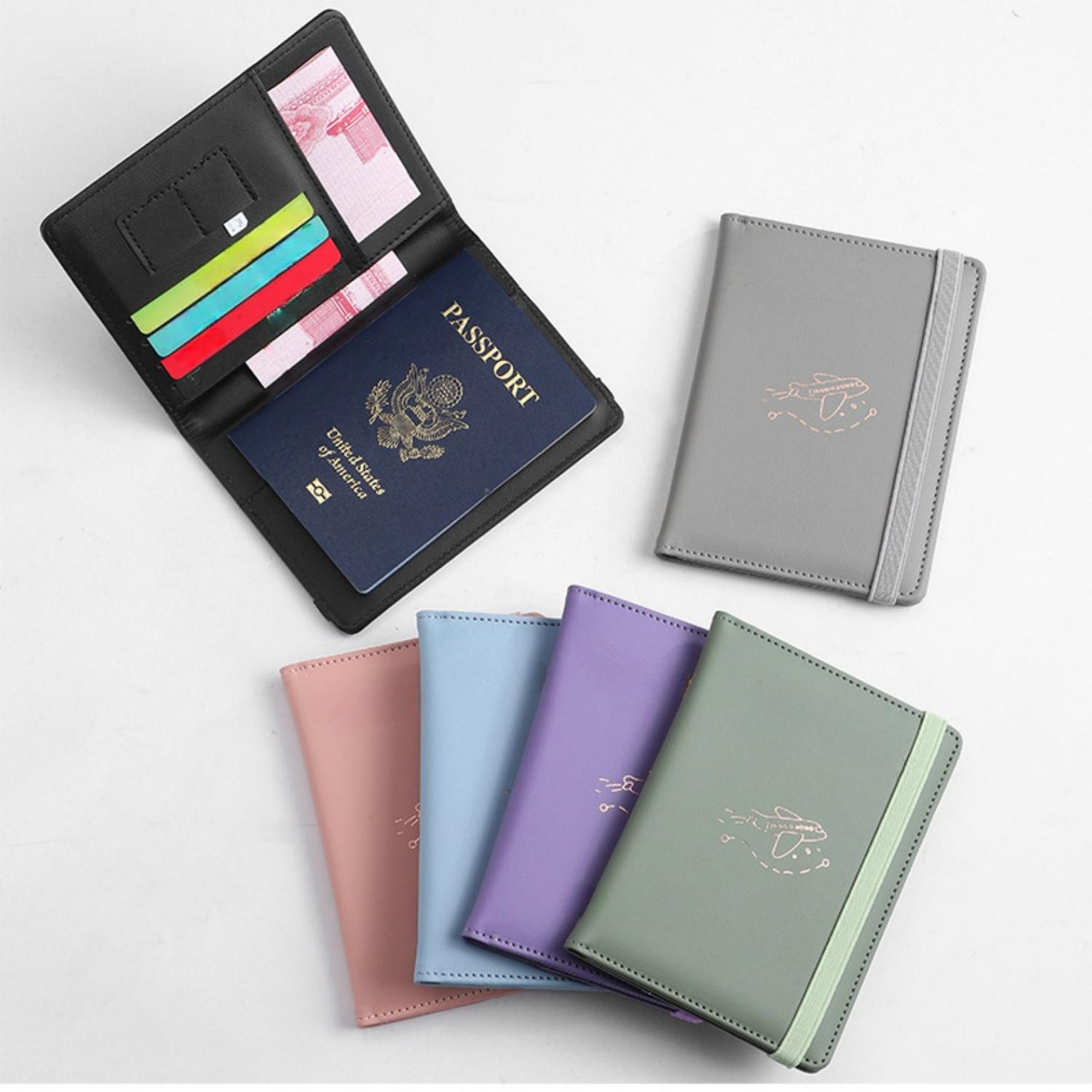 Ein offenes schwarzes Etui mit einem US-Reisepass, Karten und Geld. Mehrere bunte Reisehüllen liegen daneben.