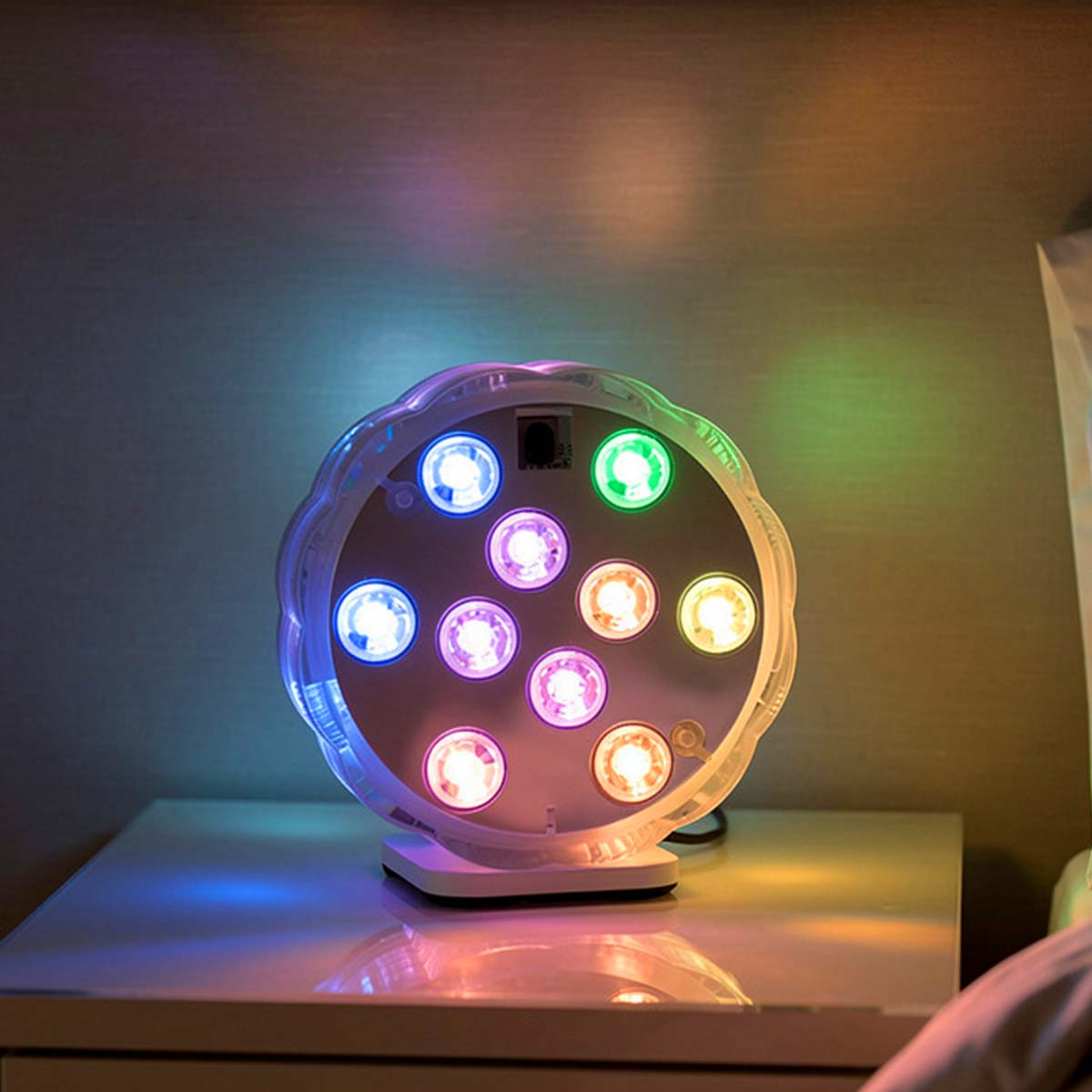 Lámpara redonda con LEDs de colores en mesita de noche.